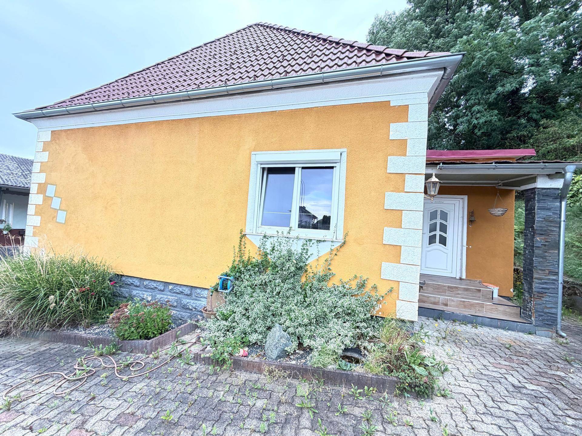 Außenansicht des zweiten Hauses mit Eingangsbereich und kleiner Gartenbepflanzung.