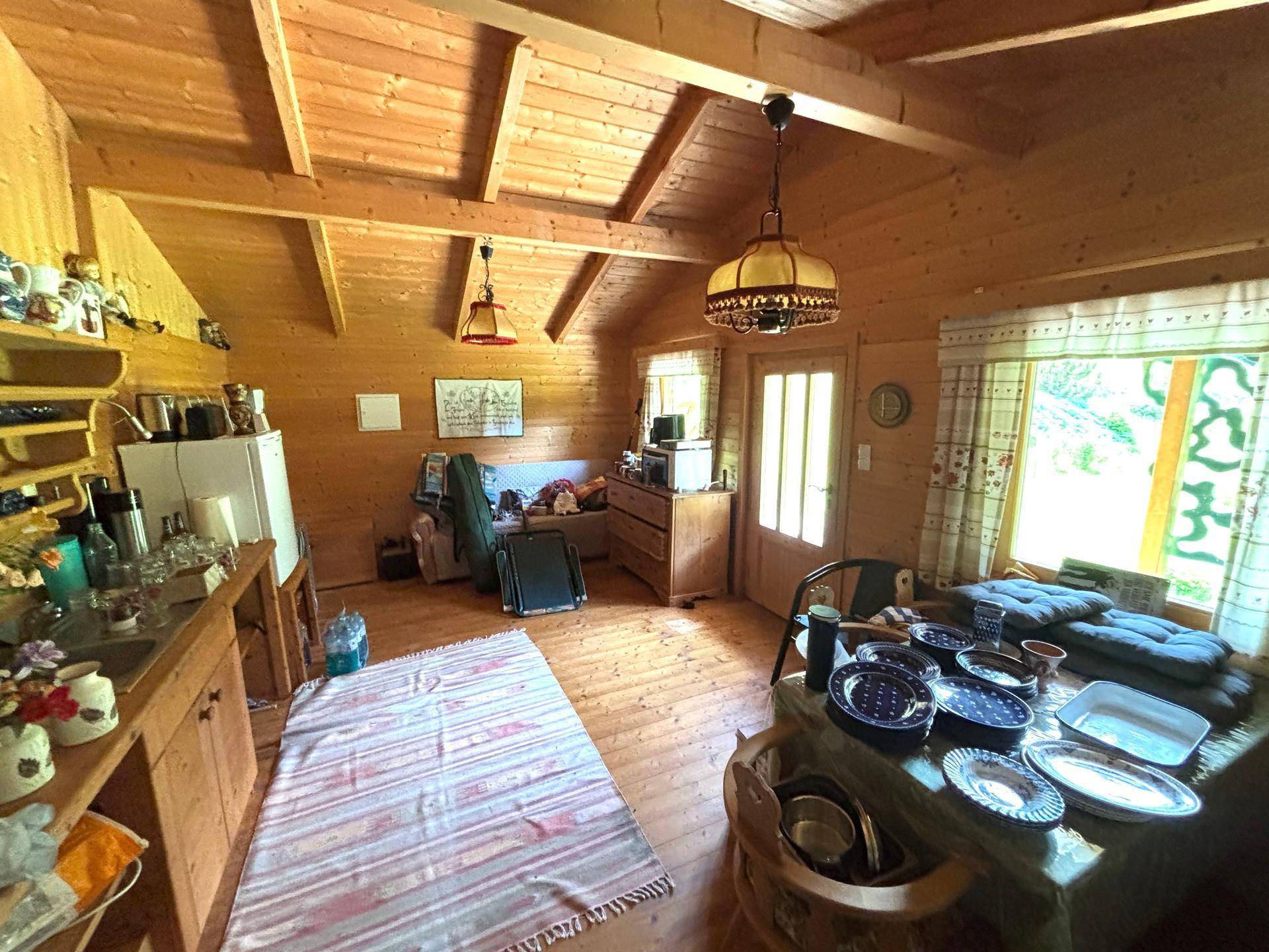 Weiterer Blick in den rustikalen Wohnbereich der Holzhütte mit Holzböden und viel Tageslicht.