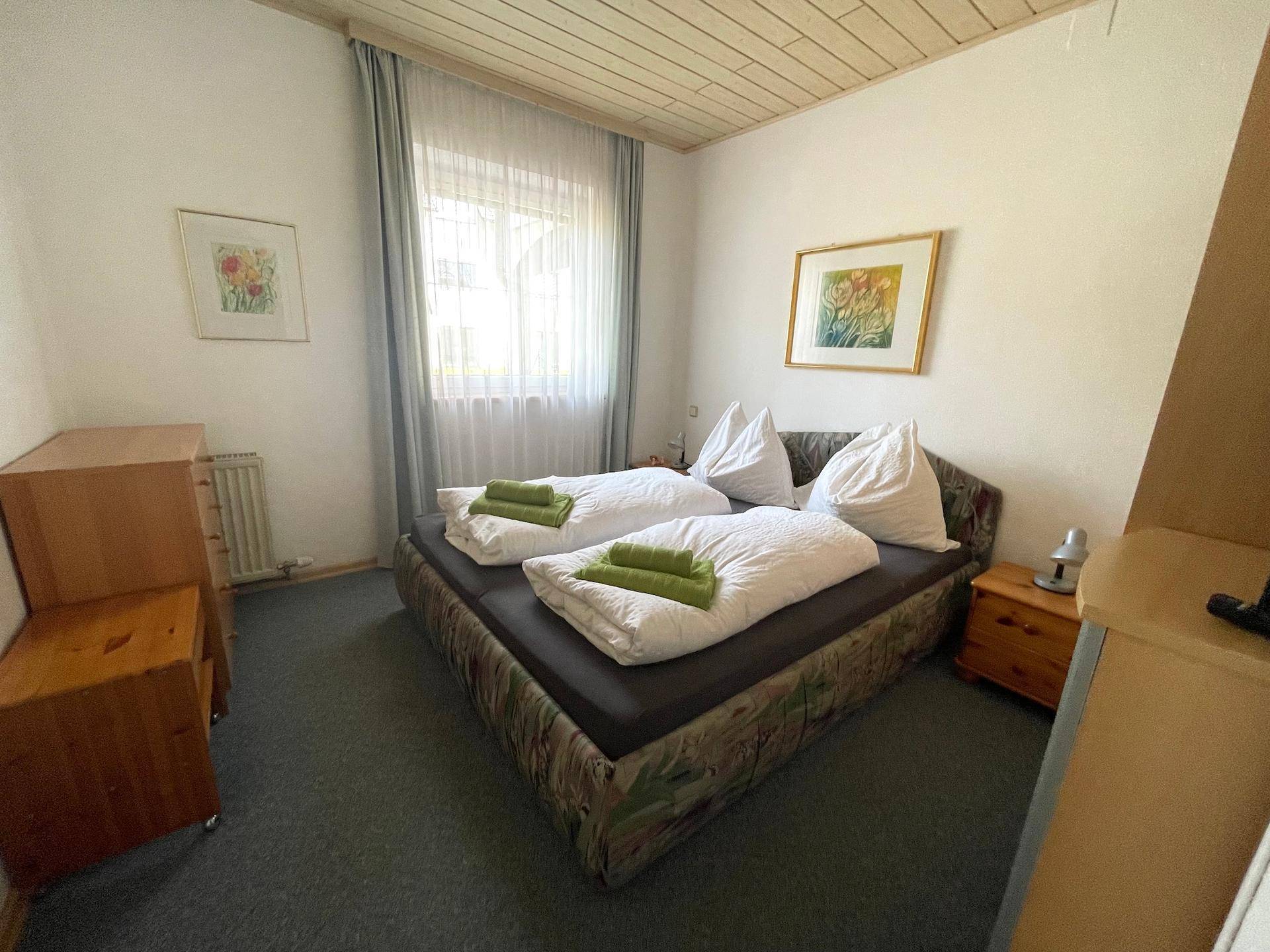 Ein Schlafzimmer mit Doppelbett, Teppichboden und einer Holzdecke.