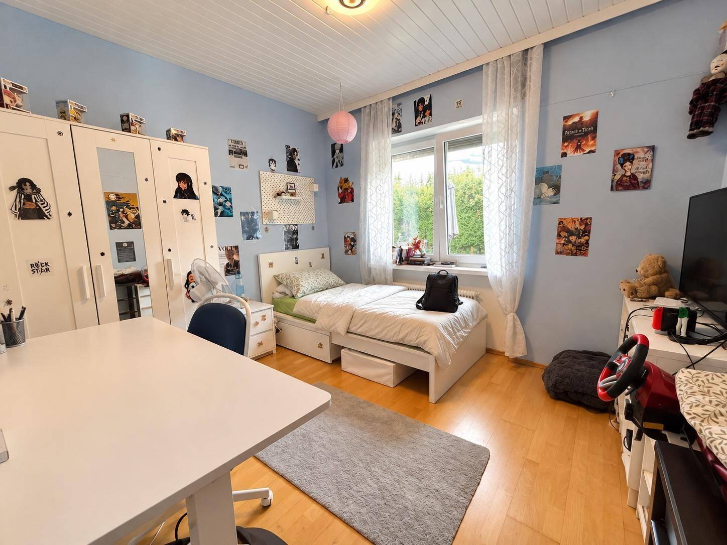 Kinderzimmer mit blau gestrichenen Wänden, Einzelbett und Schreibtisch, hell und freundlich.