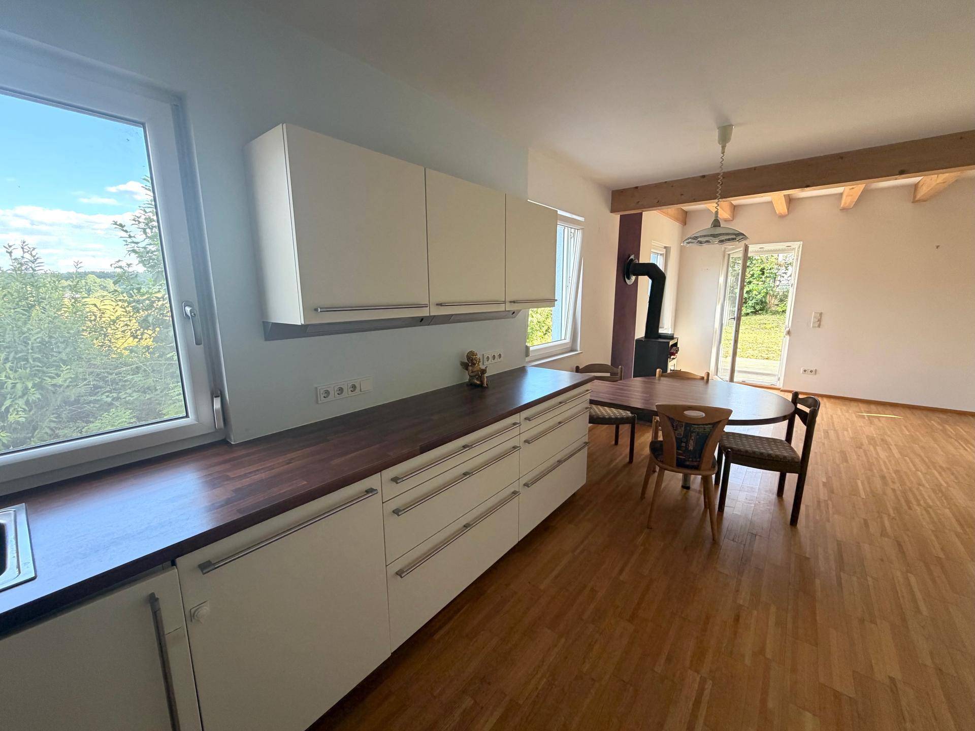 Offene Küche mit Essbereich, Holzbalken und weitem Blick in die umliegende Landschaft.