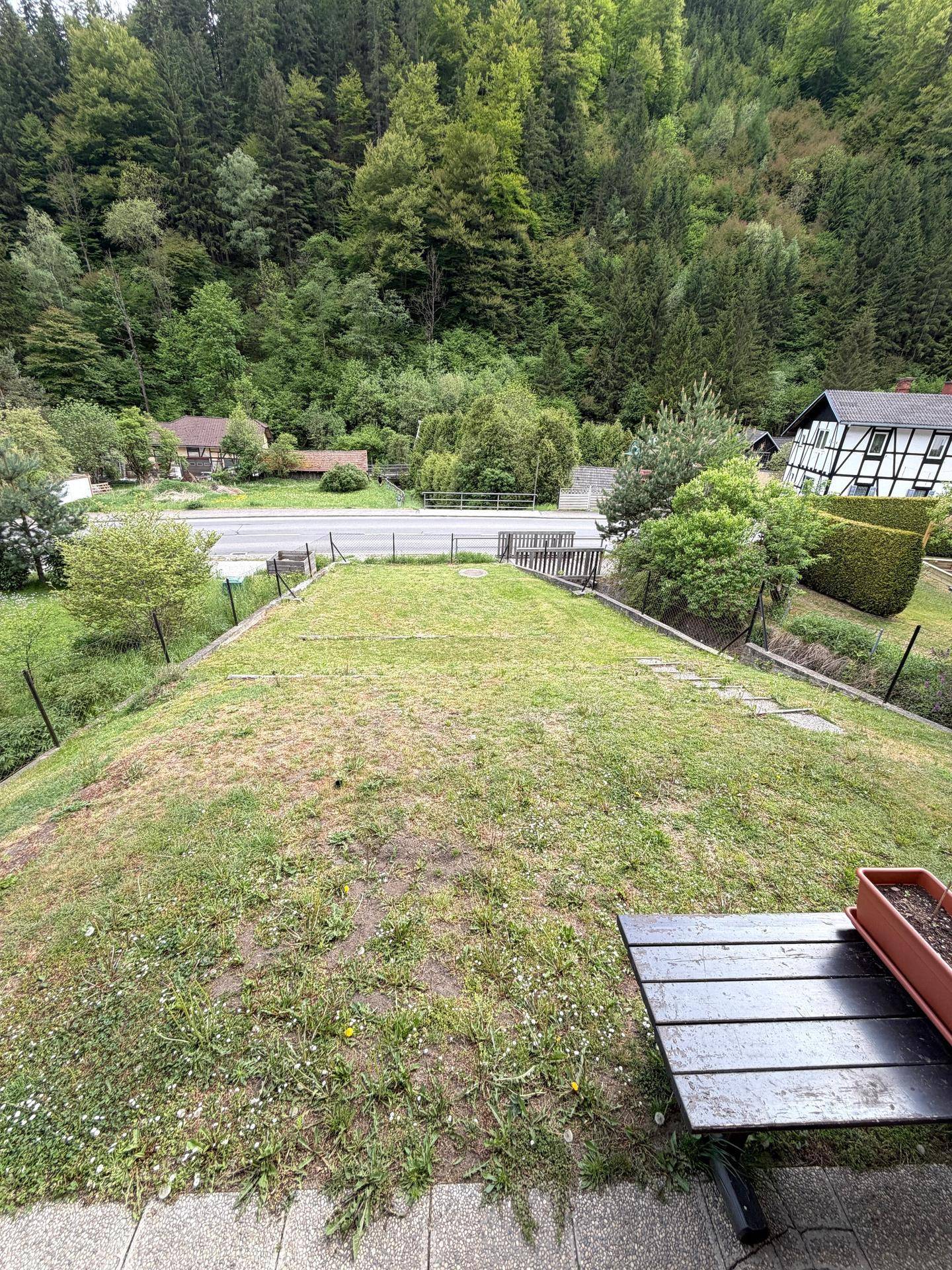 Großer Gartenbereich mit Rasenfläche und Blick auf die umliegende Landschaft und Straße.