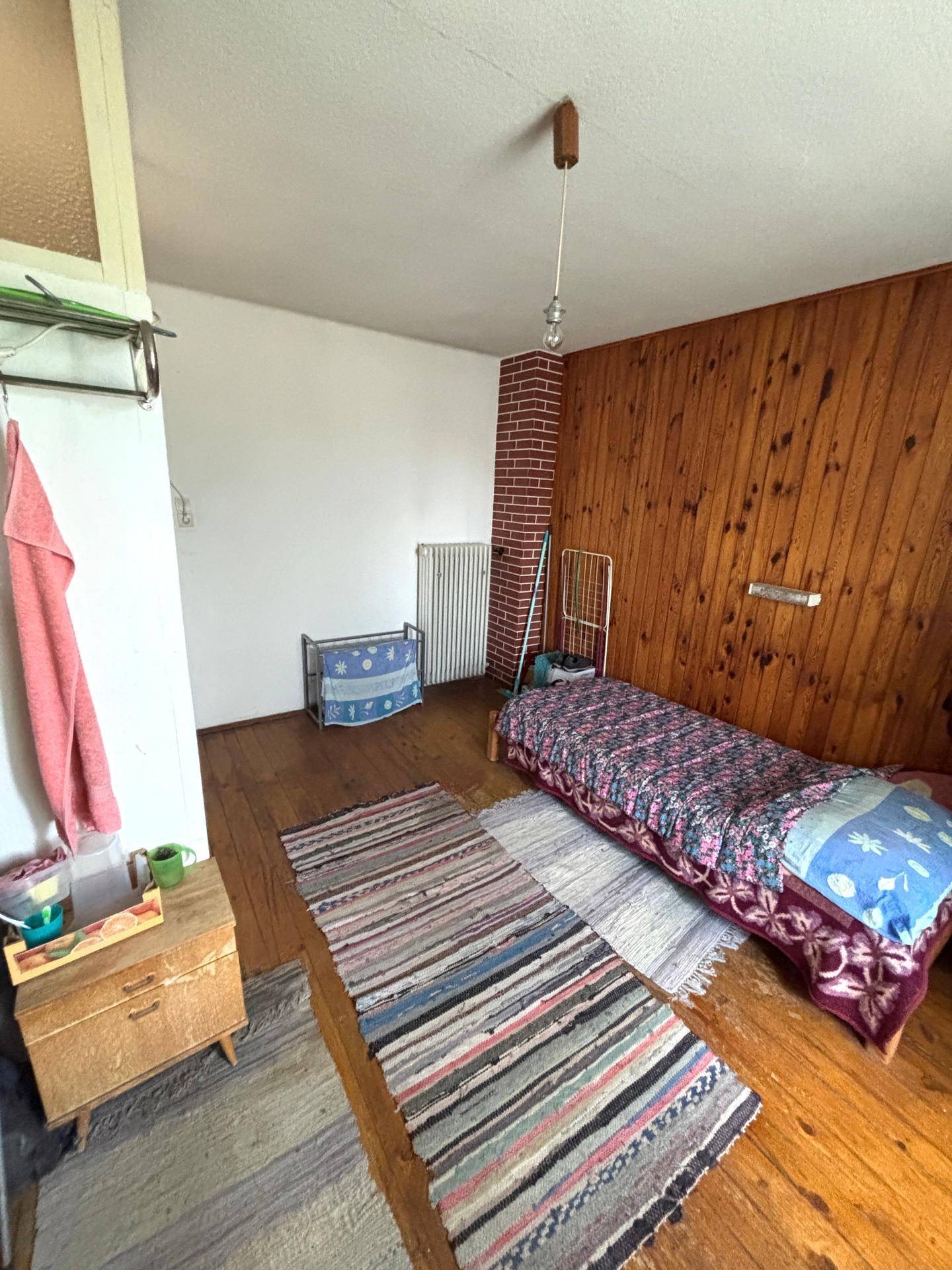 Schlafzimmer mit Holzwänden, Holzboden und Einzelbett, mit Teppichläufern.