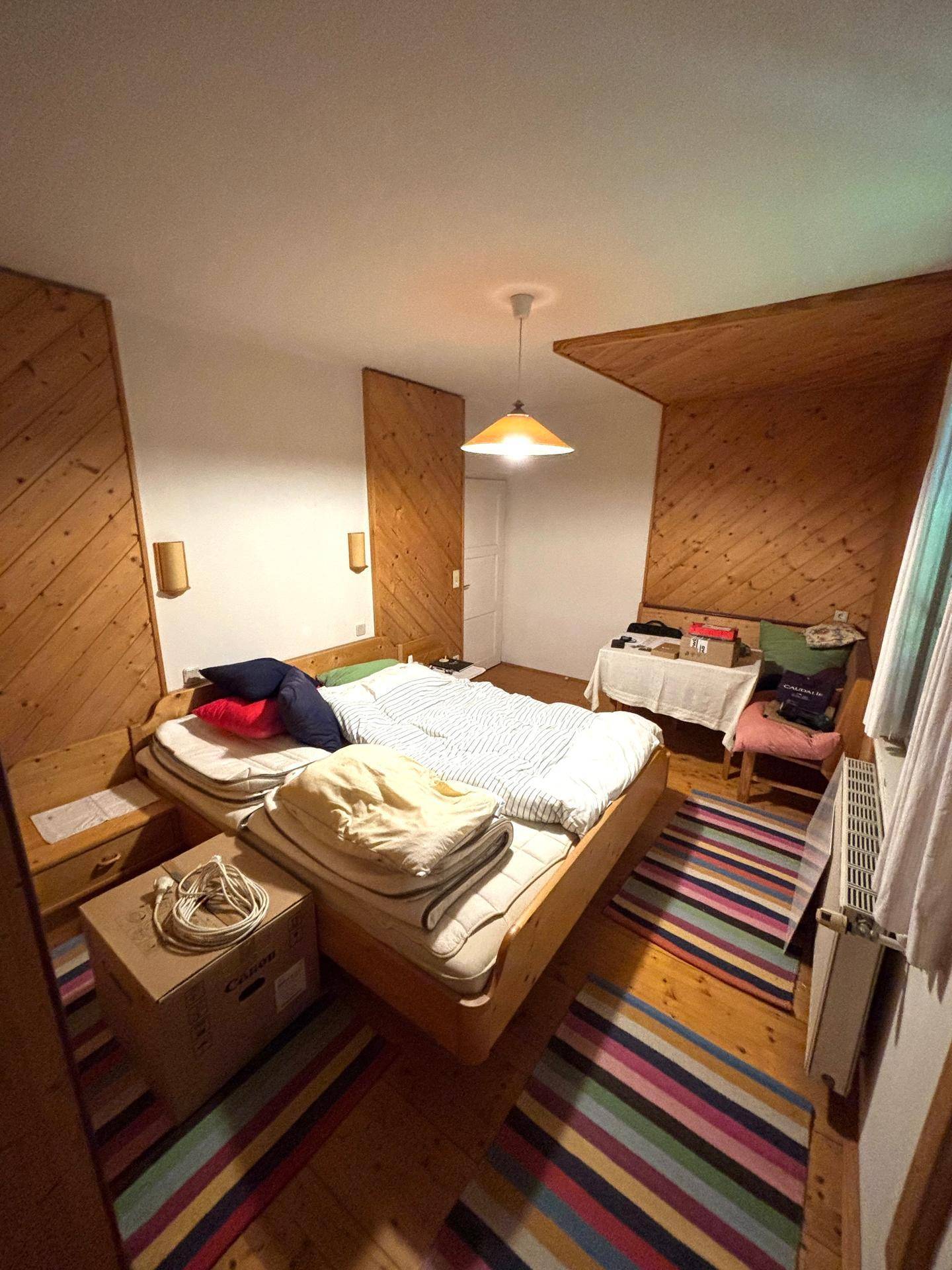Geräumiges Schlafzimmer mit Holzboden, Holzdecke und mehreren Betten.