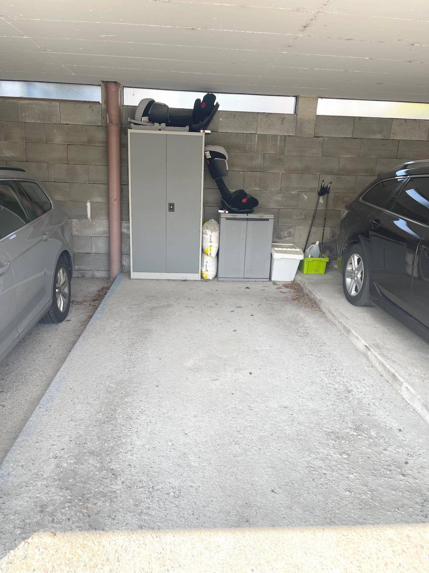 Überdachter Stellplatz für Fahrzeuge mit Lagerfläche im Hintergrund.