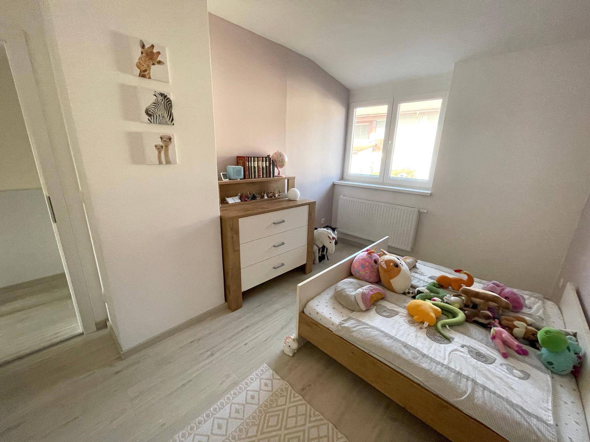 Kinderzimmer mit Bett, Kommode und Fenster, hell und freundlich gestaltet.