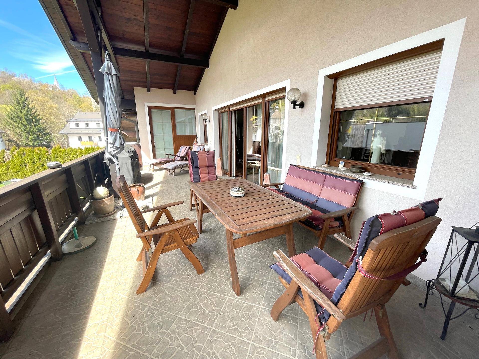 Ein großer Balkon mit Holzmöbeln und Blick auf die grüne Hügellandschaft.
