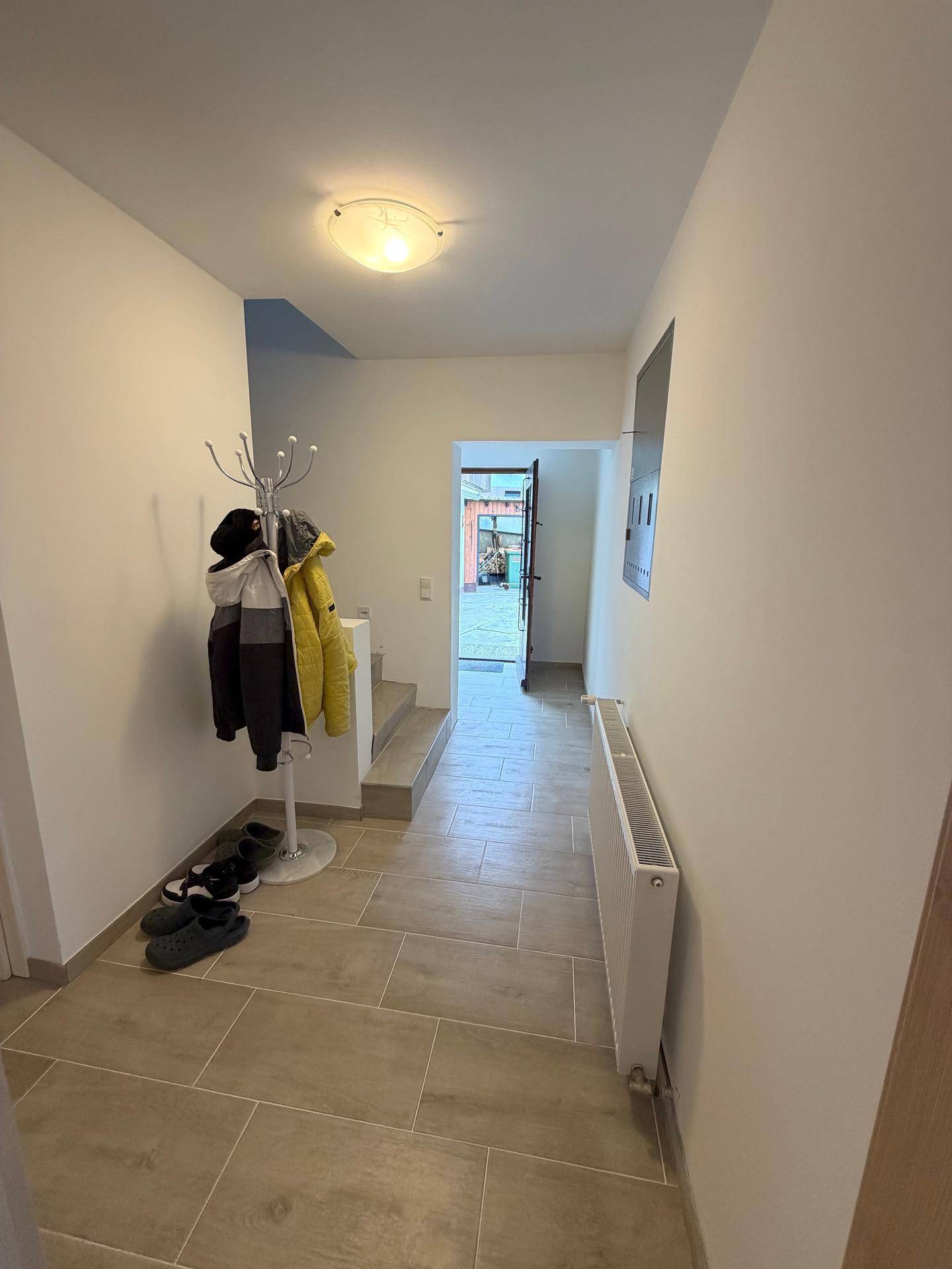 Heller Flur mit Fliesenboden, Garderobe und Zugang zu weiteren Räumen und Treppe.