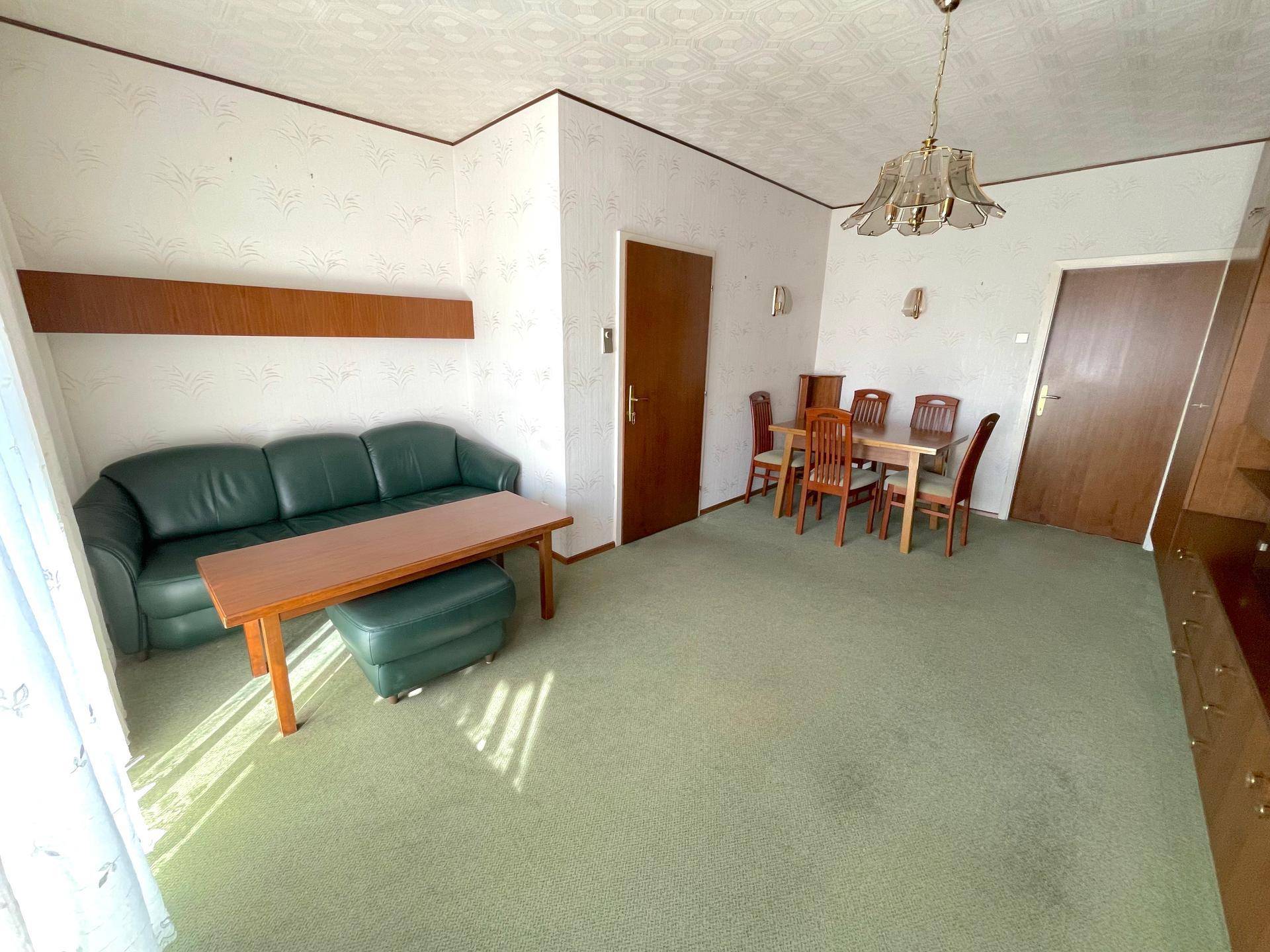 Geräumiger Wohn-Essbereich mit Sofa, Esstisch und Teppichboden, hell und funktional.