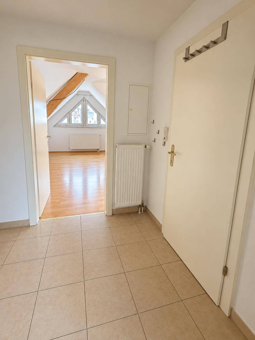 Heller Flur mit Fliesenboden und Zugang zu weiteren Räumen, inklusive Heizkörper.
