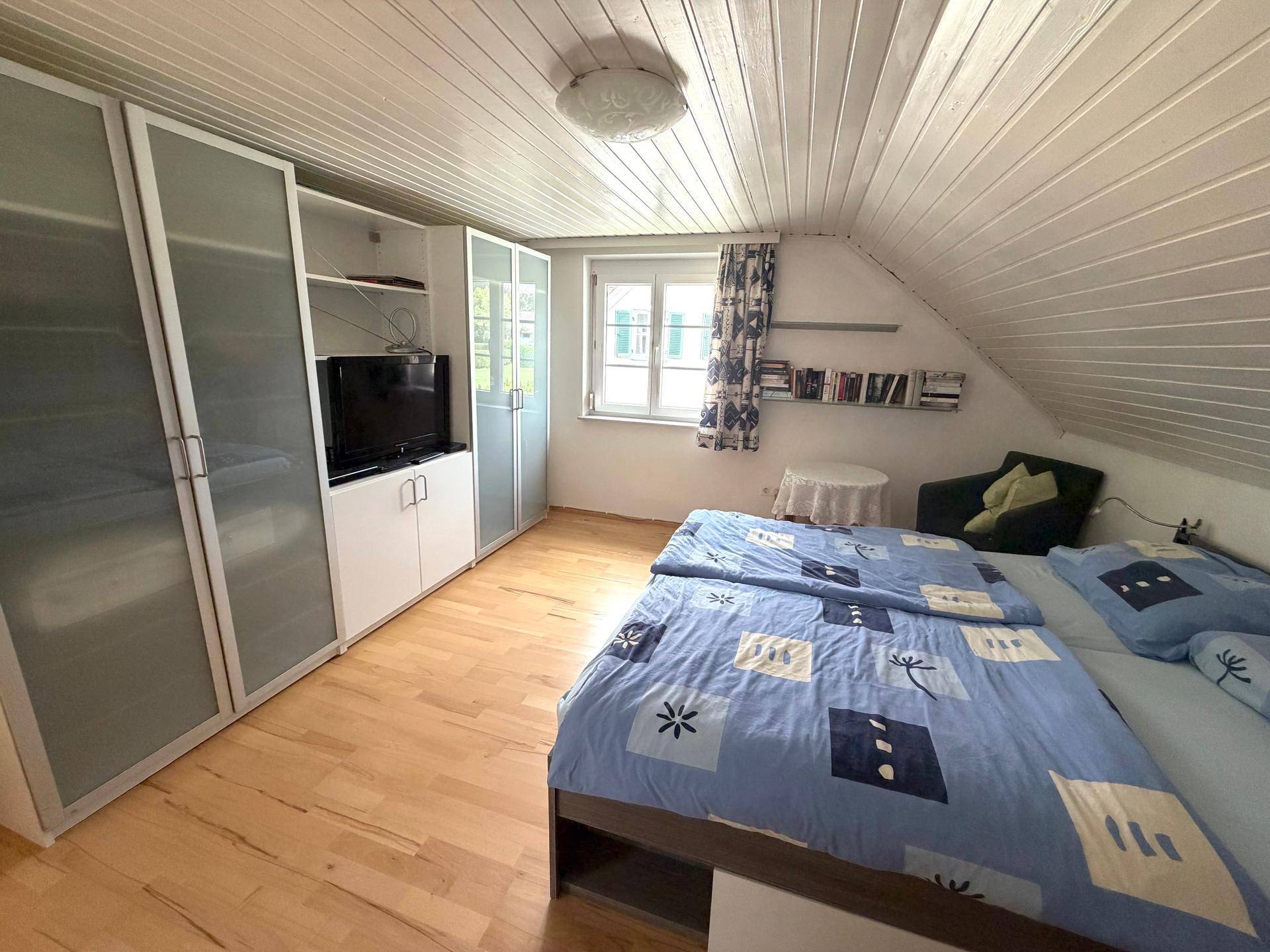 Schlafzimmer mit großem Kleiderschrank, Doppelbett und Holzboden.