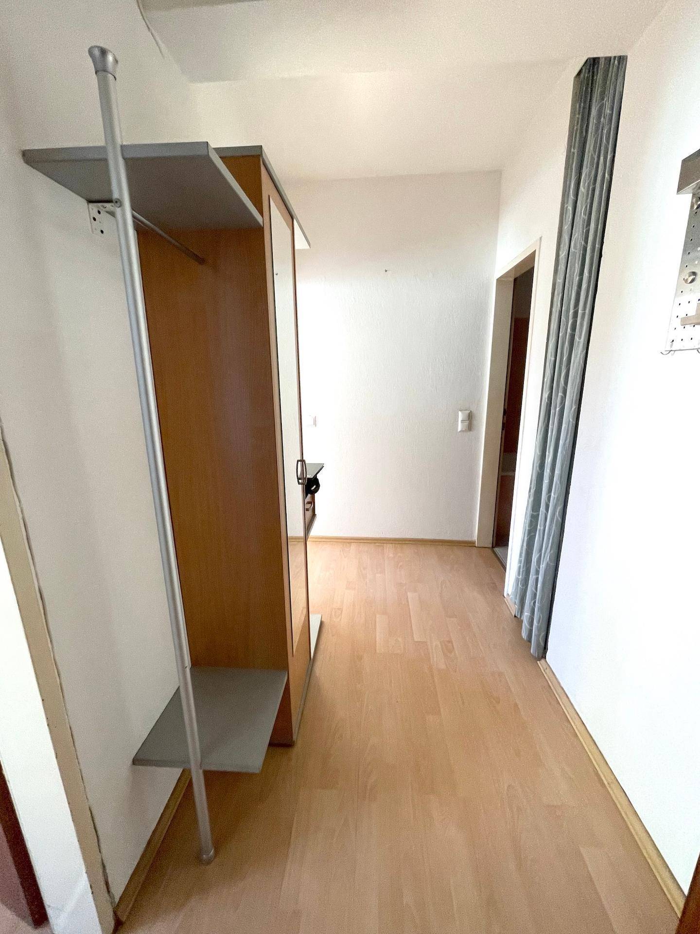 Heller Flur mit Parkettboden und praktischer Garderobe mit Spiegel.