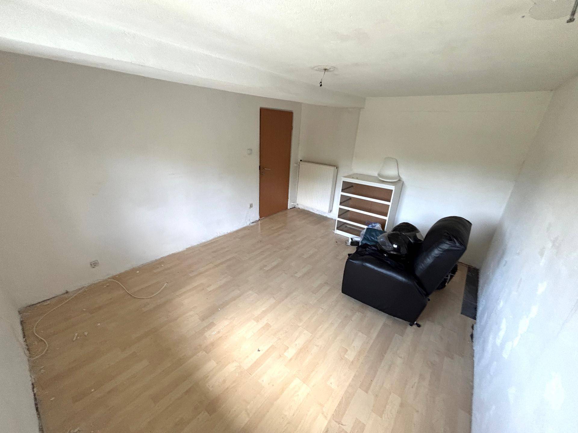 Helles Zimmer mit hellem Laminatboden, weißen Wänden und einem Fenster.