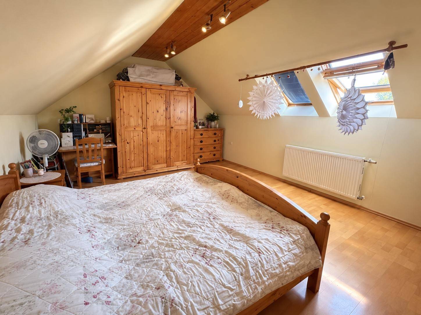 Helles Dachschlafzimmer mit Holzbett, Kleiderschrank und Dachfenstern für viel Licht.