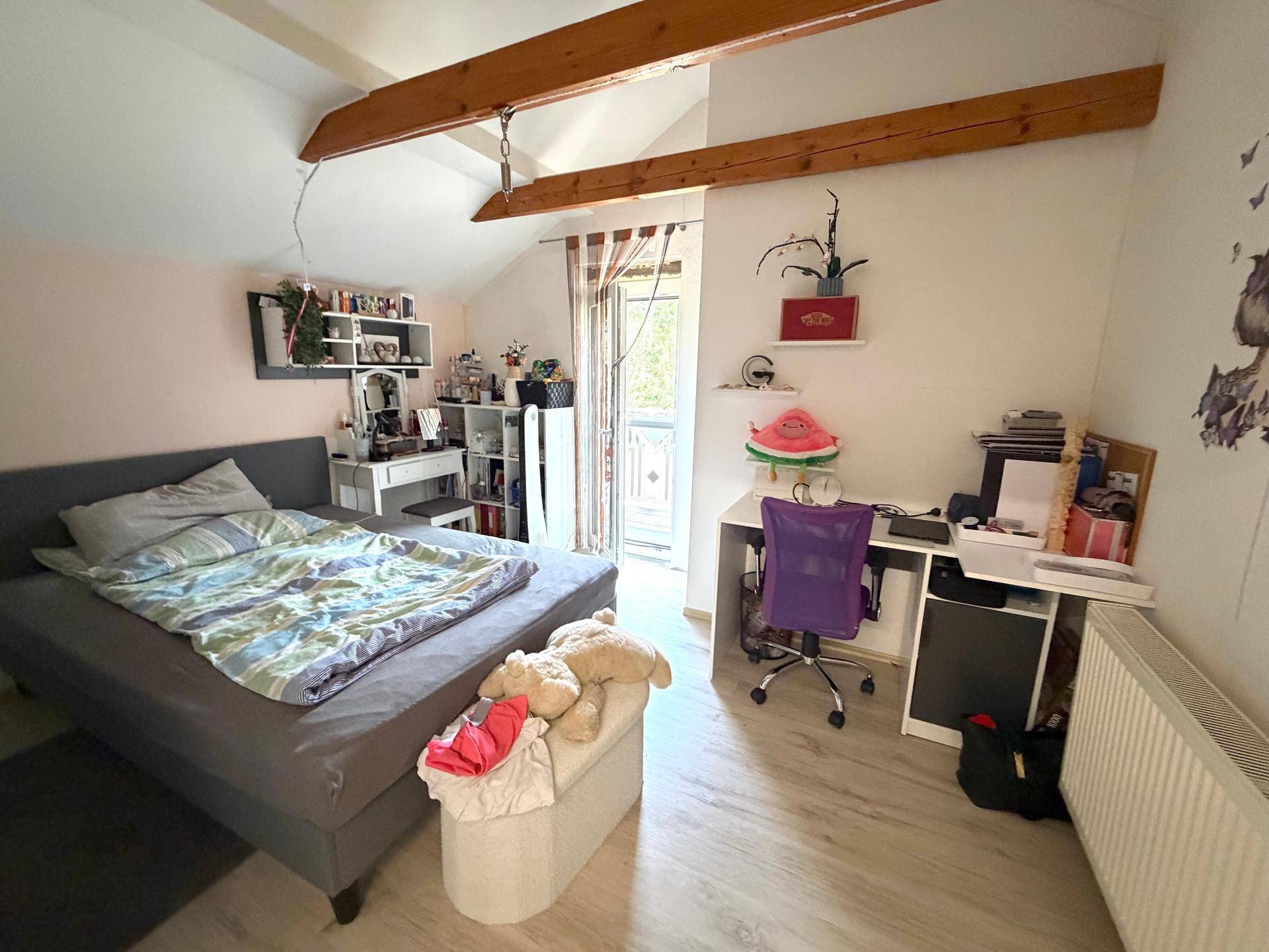 Helles Schlafzimmer mit Doppelbett, Schreibtisch und Zugang zu einem französischen Balkon.