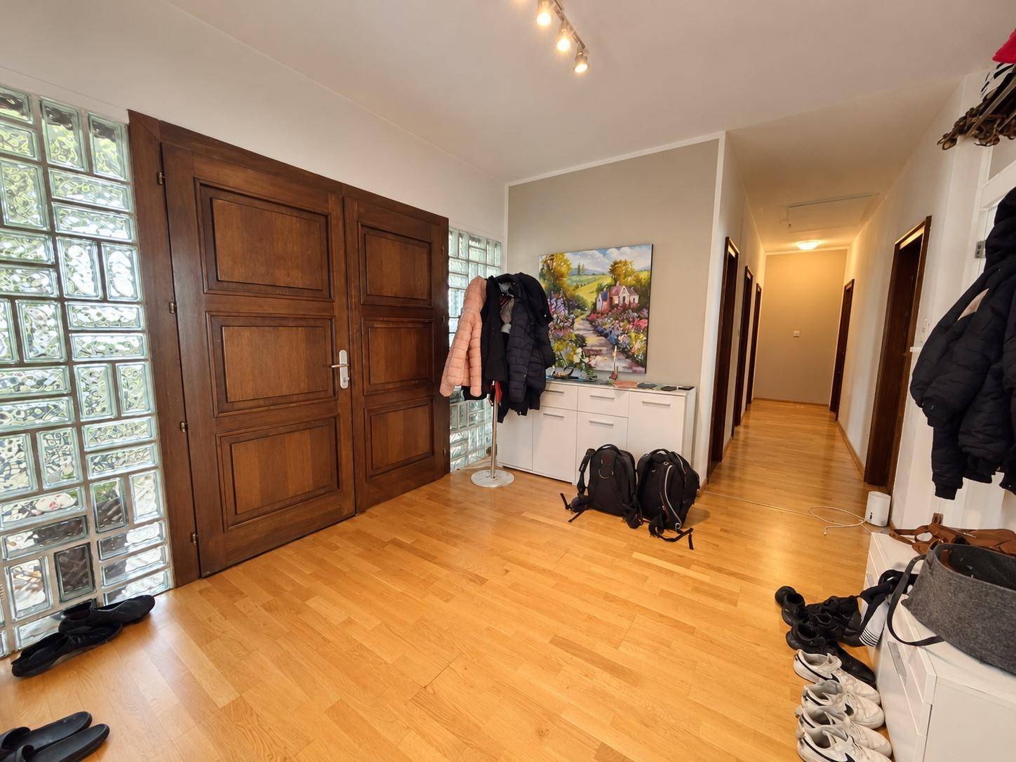 Geräumiger Eingangsbereich mit hellem Holzparkettboden und einer dekorativen Glasbausteinwand.