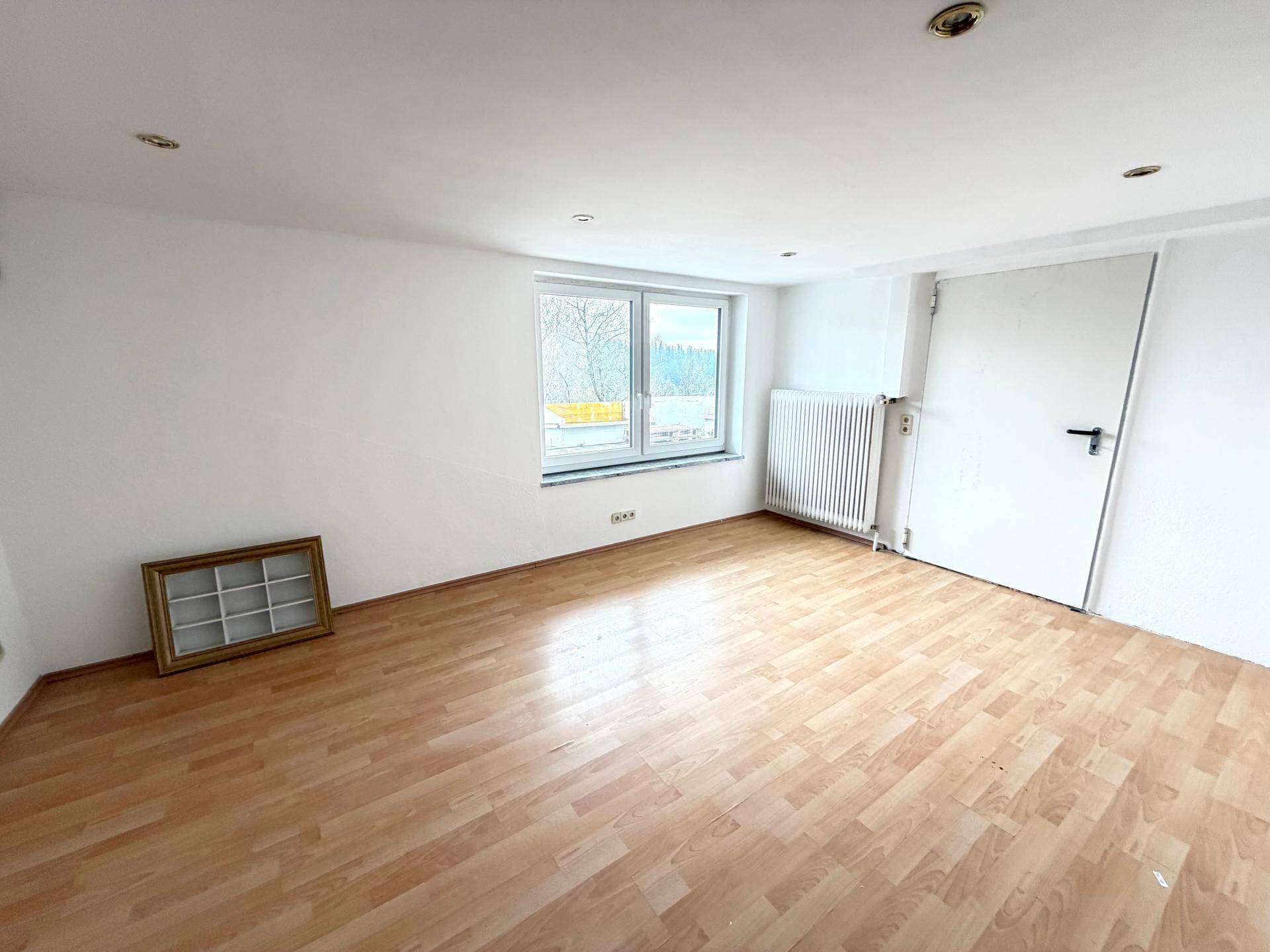 Geräumiges Zimmer mit Holzboden, weißen Wänden und Blick ins Grüne, ideal als Schlafzimmer.