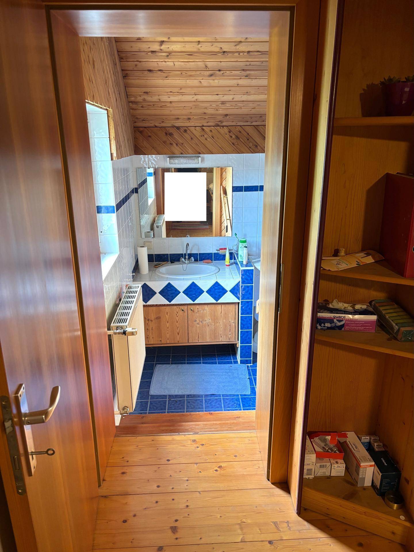Badezimmer mit blauen und weißen Fliesen, Holzdecke und Fenster.