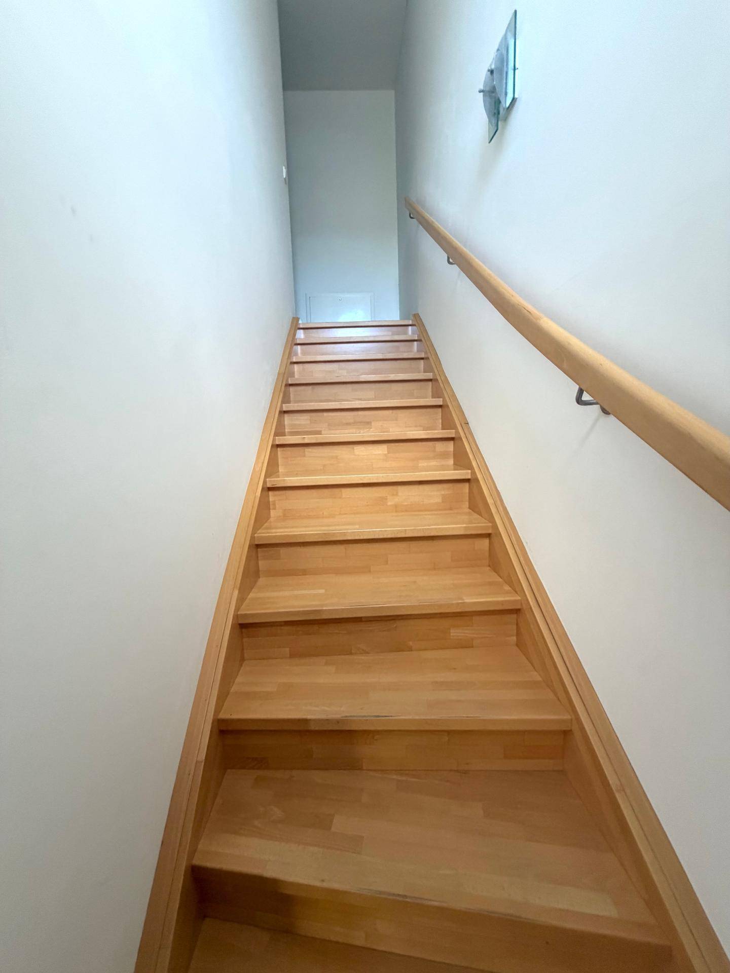 Holztreppe mit Handlauf führt in das obere Stockwerk des Hauses.