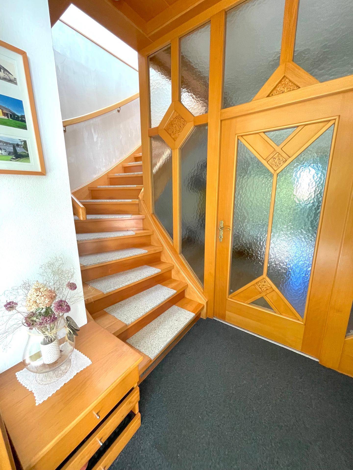 Elegante Holztreppe mit Teppichläufern, die die oberen Etagen stilvoll und sicher verbindet.