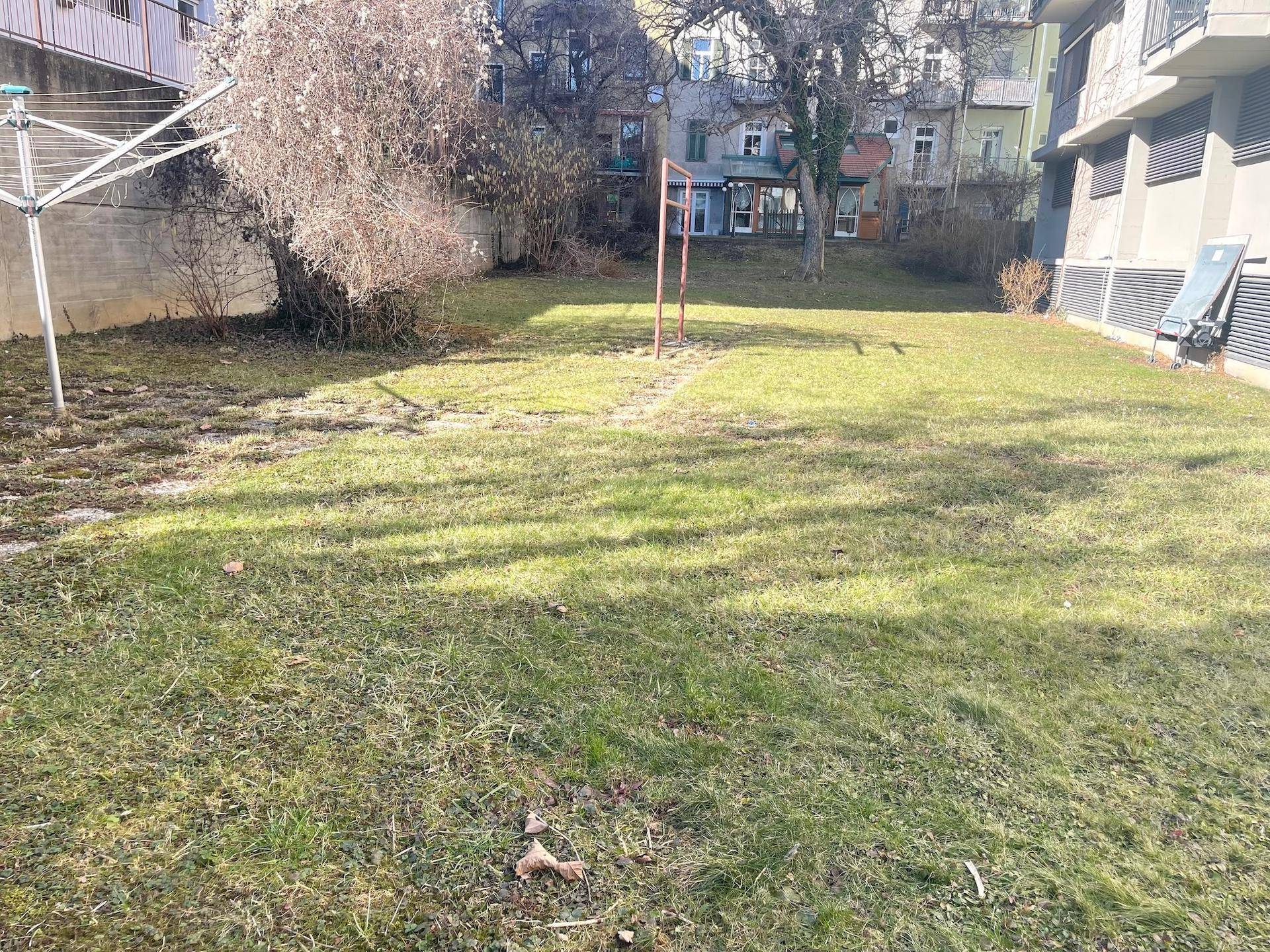 Gemeinschaftlicher Gartenbereich mit Rasenfläche und Wäscheständer.