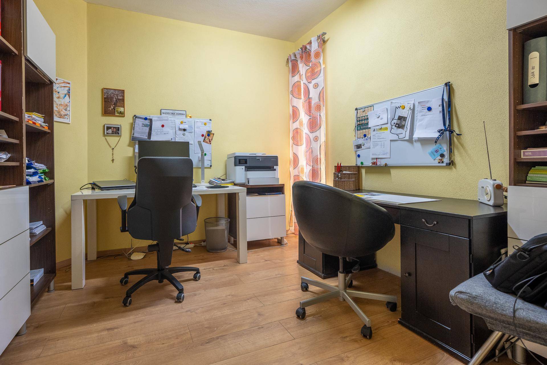Helles Arbeitszimmer mit zwei Schreibtischen, Holzfußboden und Bücherregalen.