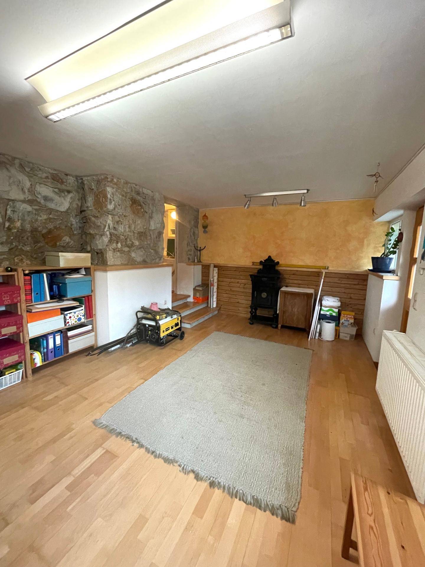 Geräumiger Kellerraum mit Holzboden und Steinwand, vielseitig nutzbar.