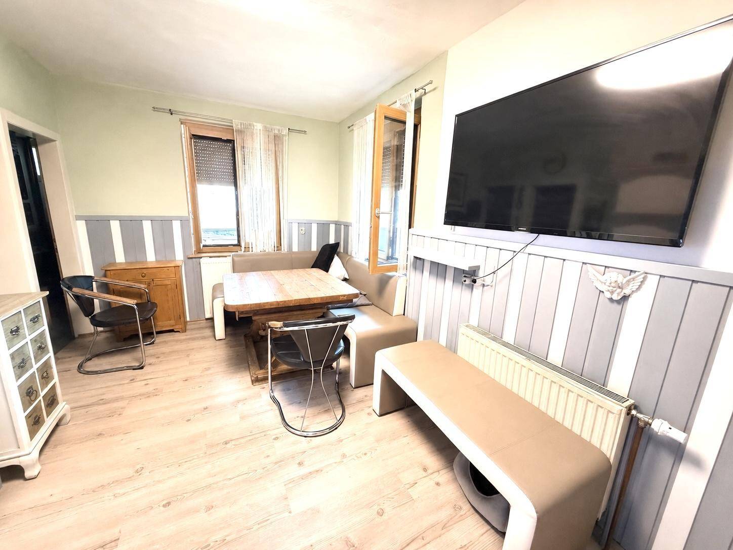 Heller Essbereich mit Holztisch, bequemer Sitzbank und Blick auf den Außenbereich.