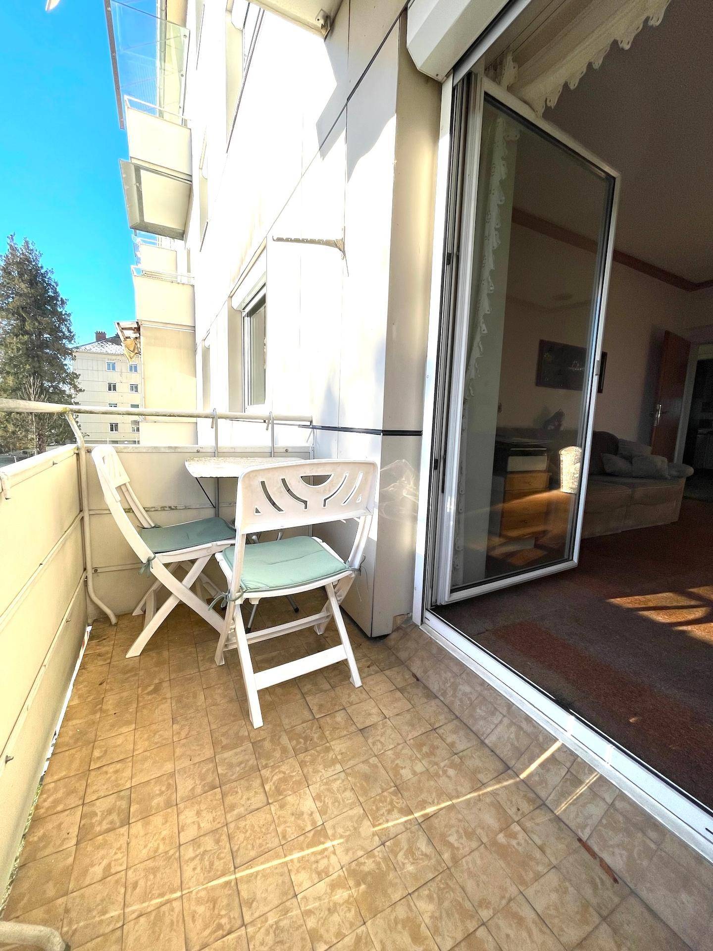 Sonniger Balkon mit Fliesenboden und Sitzgelegenheiten, ideal zum Entspannen.