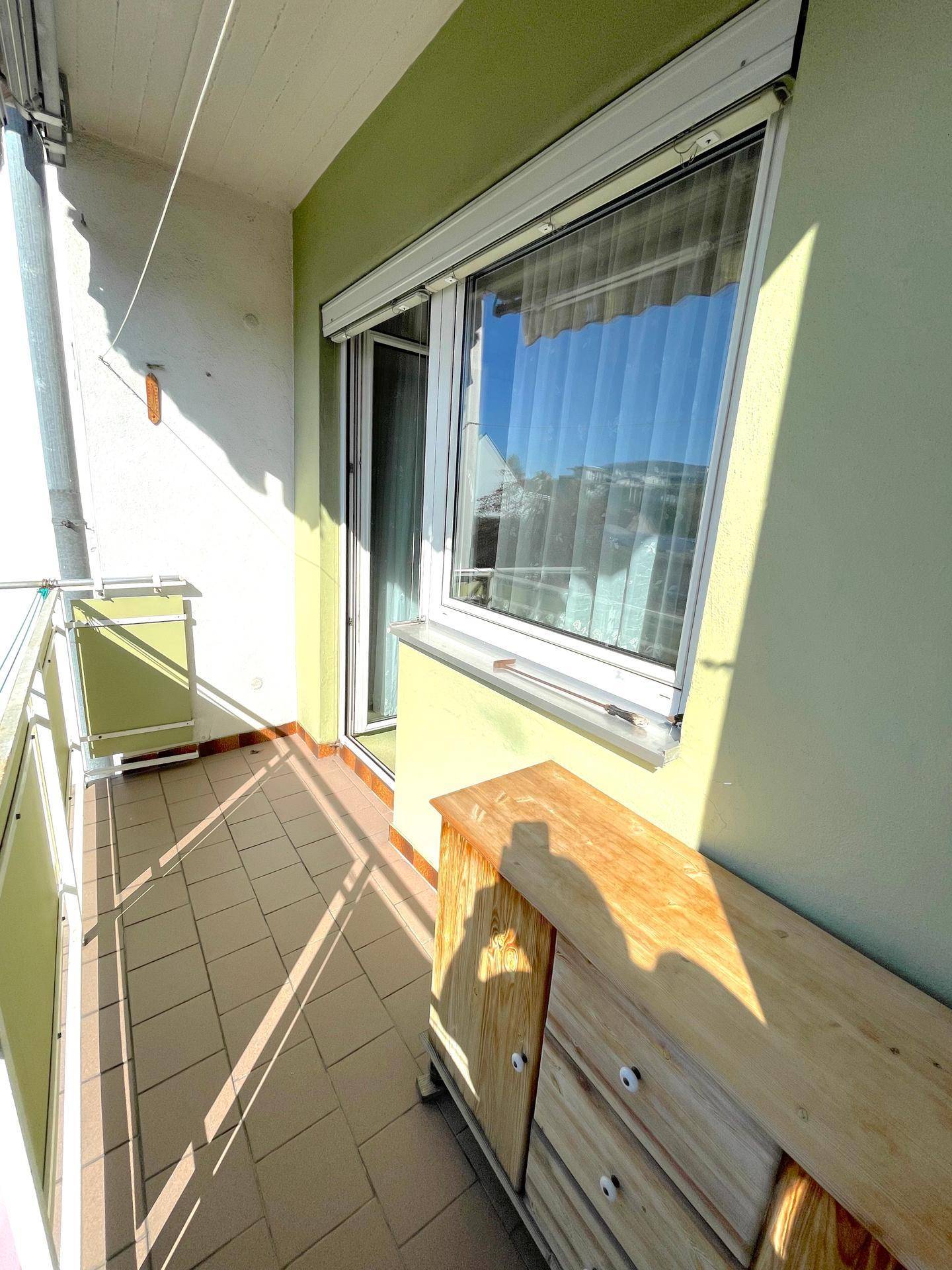 Sonniger Balkon mit Fliesenboden und Blick auf die Umgebung, ideal für Entspannung.