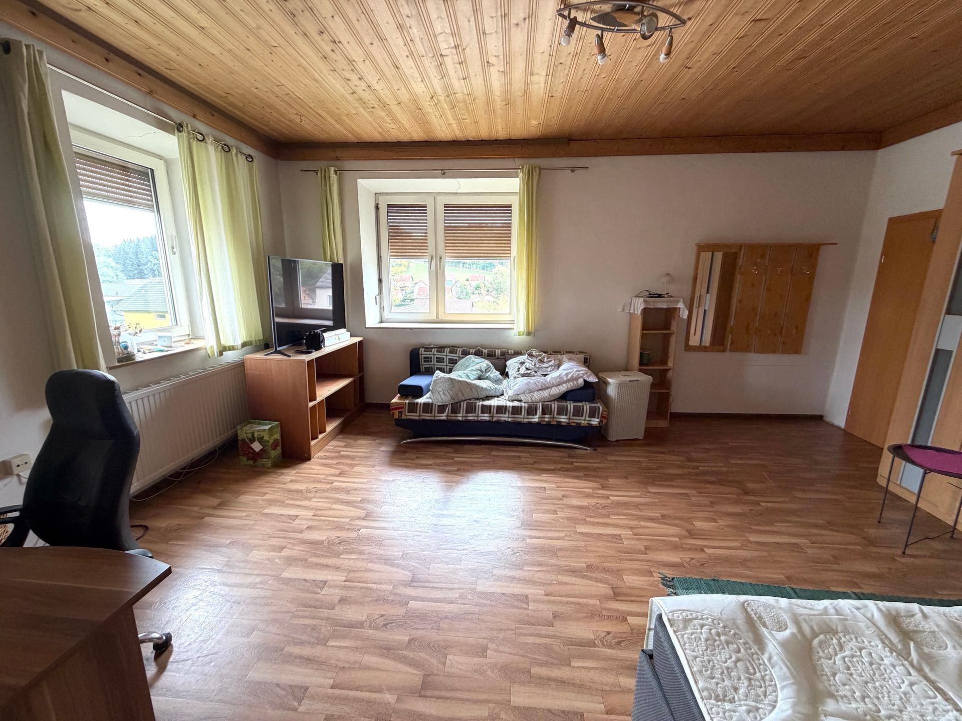 Geräumiges Schlafzimmer mit Laminatboden, Holzdecke und mehreren Fenstern.
