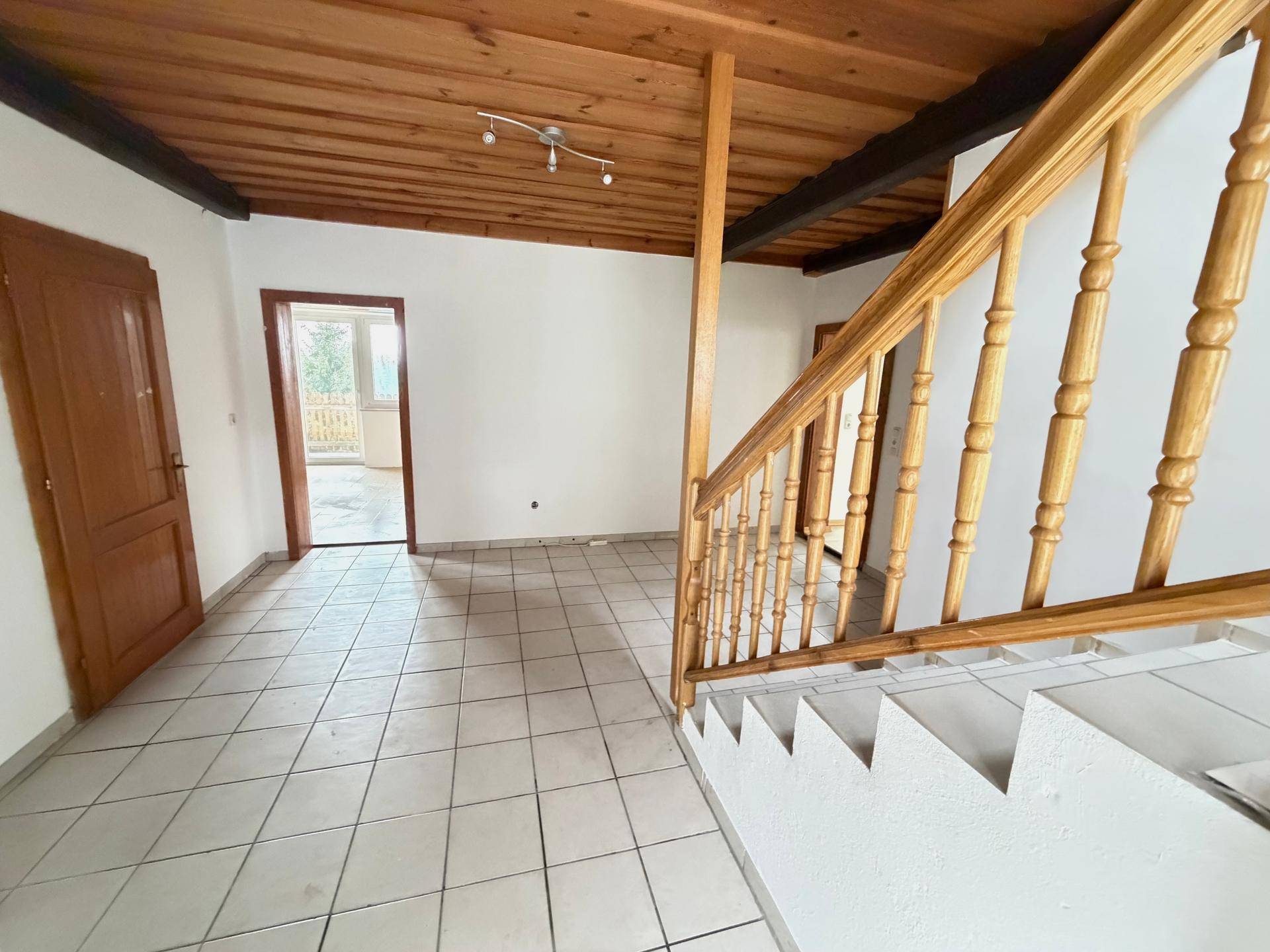 Geräumiger Flur mit Holztreppe, Fliesenboden und traditioneller Holzdecke, führt zu weiteren Räumen.