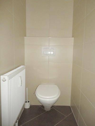 Separates WC mit Wand-WC und Heizkörper, gefliest in hellem Beige.