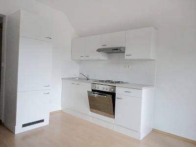 Moderne Einbauküche in Weiß mit Kochfeld, Backofen und Dunstabzugshaube.