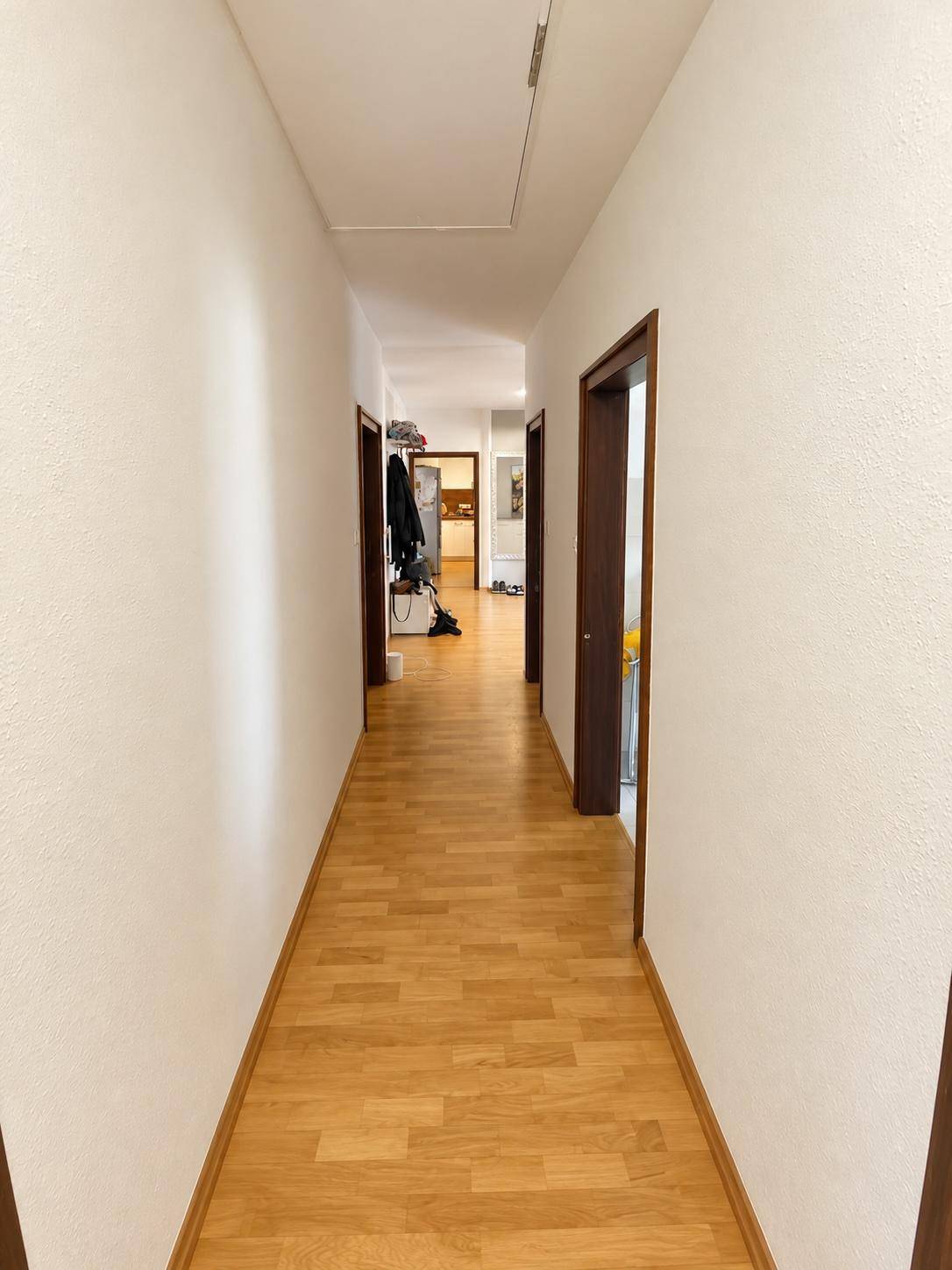 Langer, heller Flur mit Holzparkettboden, der zu verschiedenen Zimmern im Haus führt.