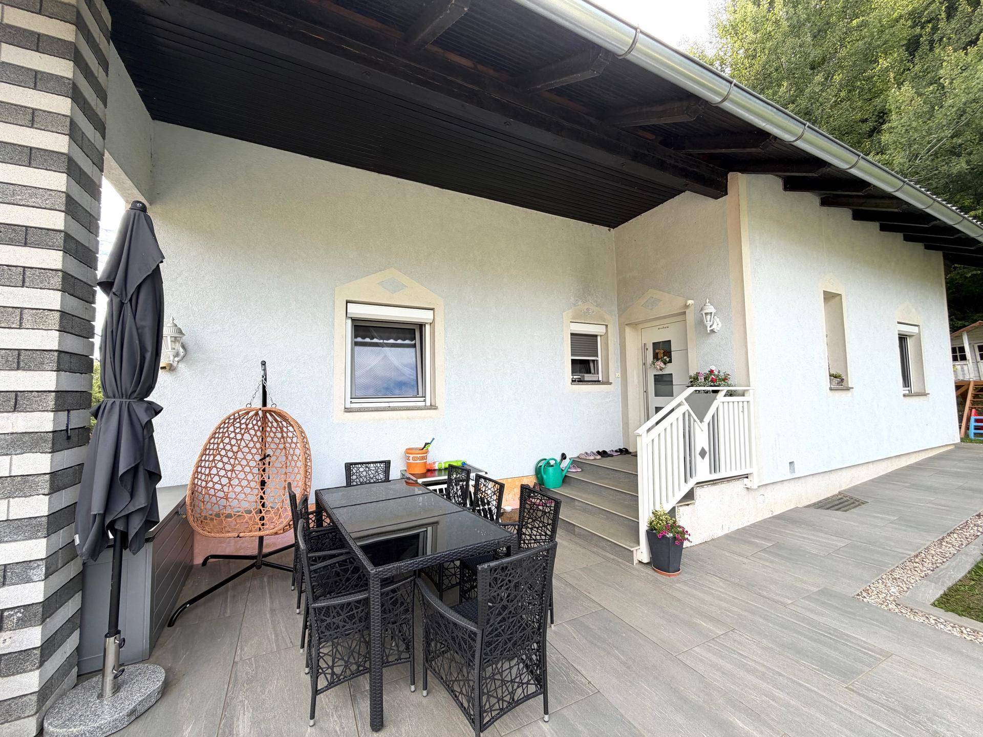 Überdachte Terrasse mit Esstisch und Stühlen, ideal für Mahlzeiten im Freien.