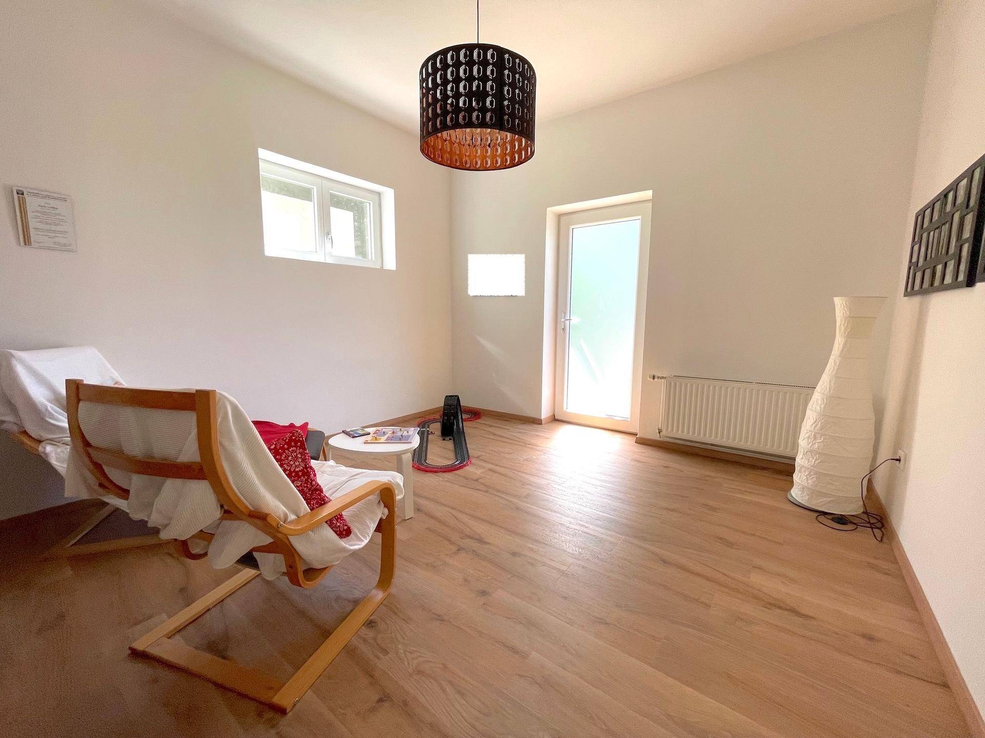 Heller Raum mit Holzboden und einem bequemen Sessel, bietet vielseitige Nutzungsmöglichkeiten.
