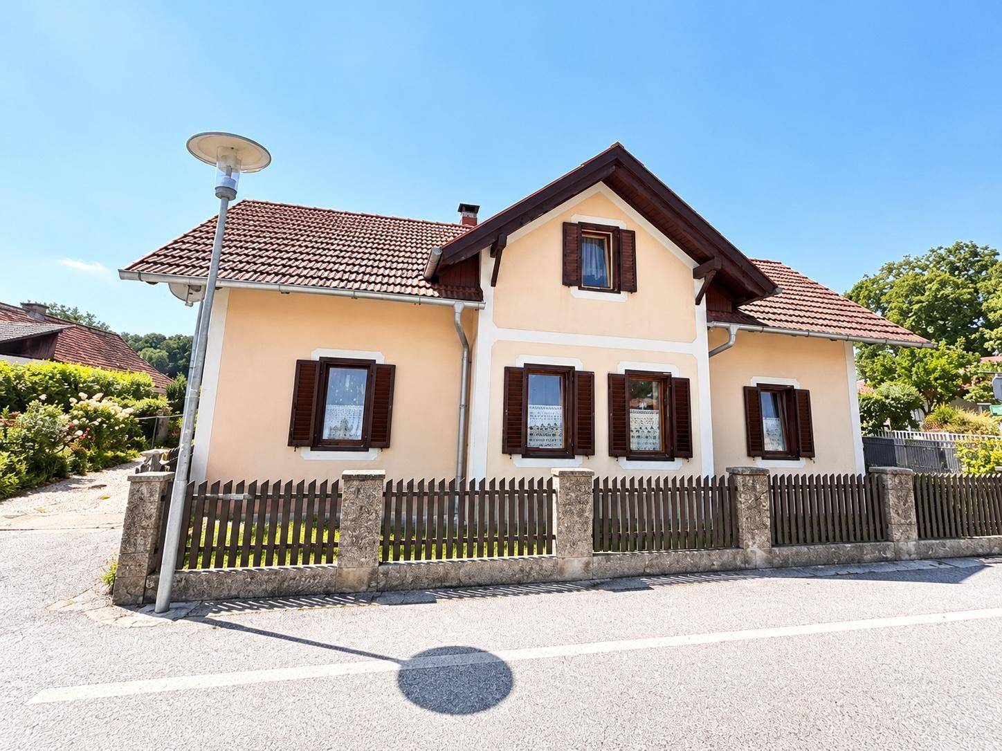 Vorderansicht eines gepflegten Einfamilienhauses mit traditioneller Architektur und Holzzaun.