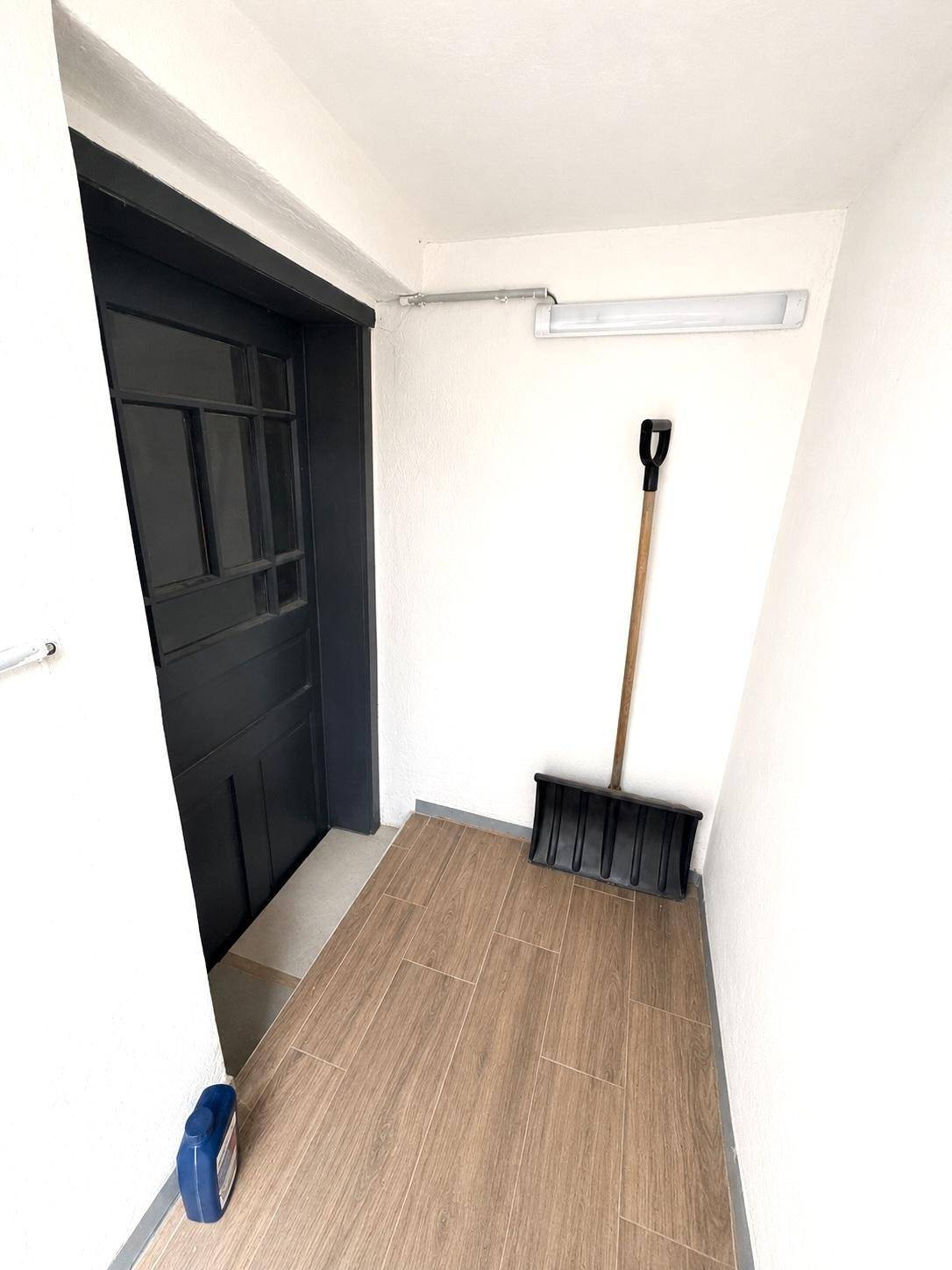 Heller Eingangsbereich mit dunkler Tür und Holzoptik-Fliesenboden.
