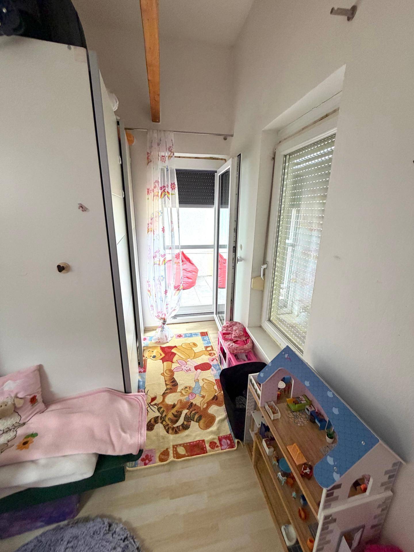 Kleiner Durchgangsbereich mit Fenster und Teppich, möglicherweise zu einem Balkon führend.