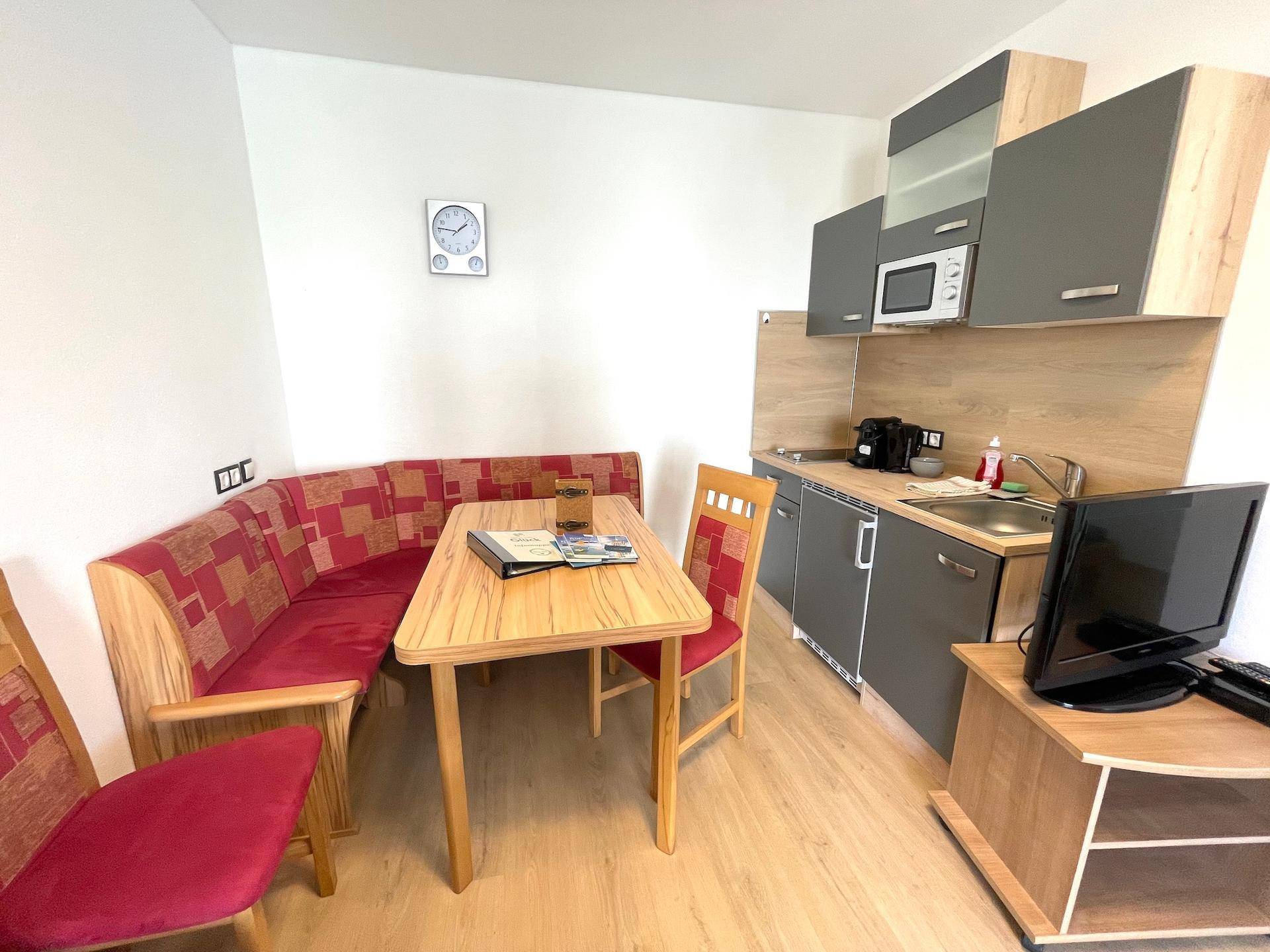 Eine kompakte Küchenzeile mit Essbereich und modernen grauen Schränken.