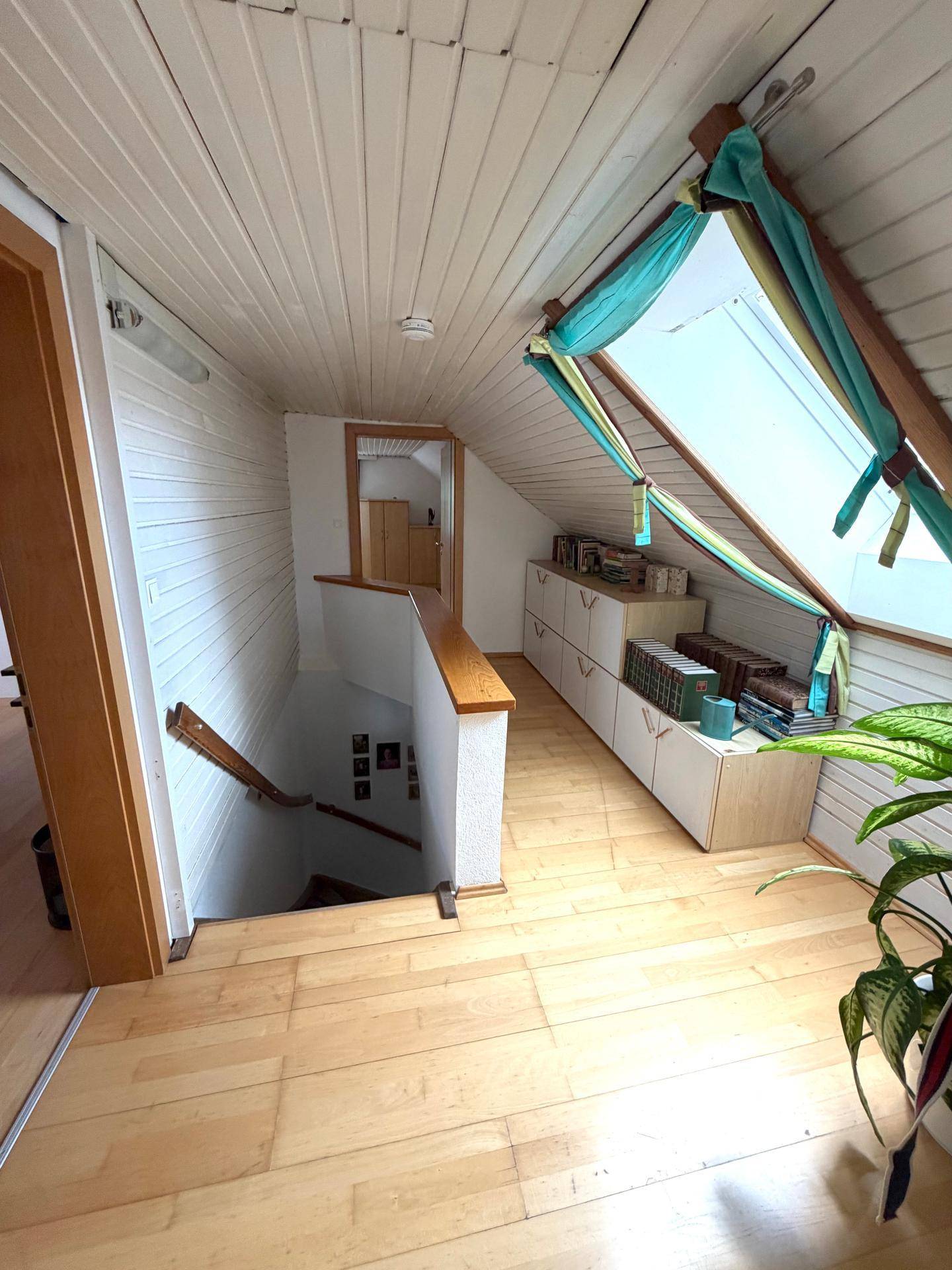 Heller Flur im Obergeschoss mit Holzboden, Dachschräge und Dachfenster.