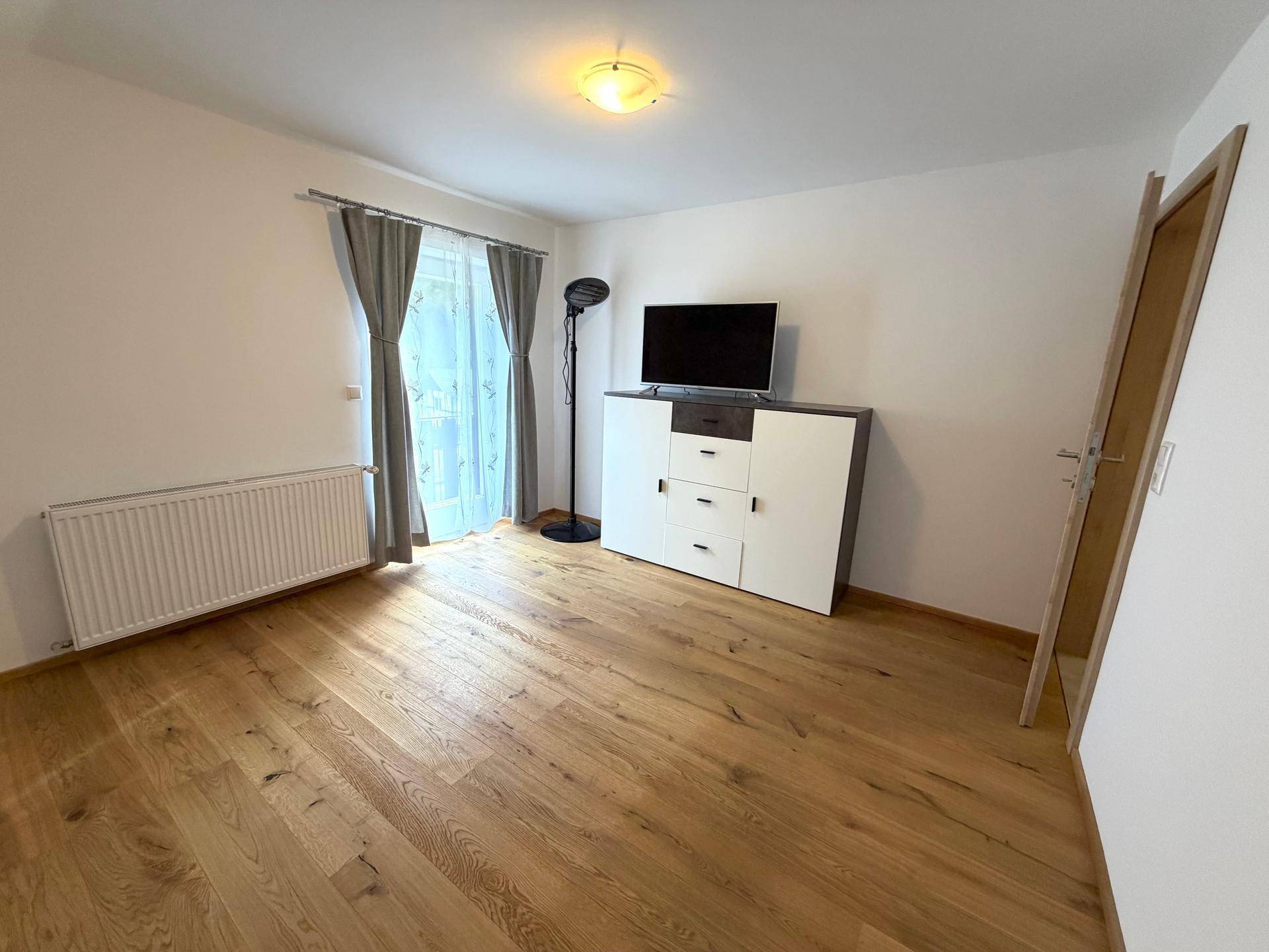 Schlafzimmer mit Holzboden, schrägen Wänden und einem modernen TV-Möbel.