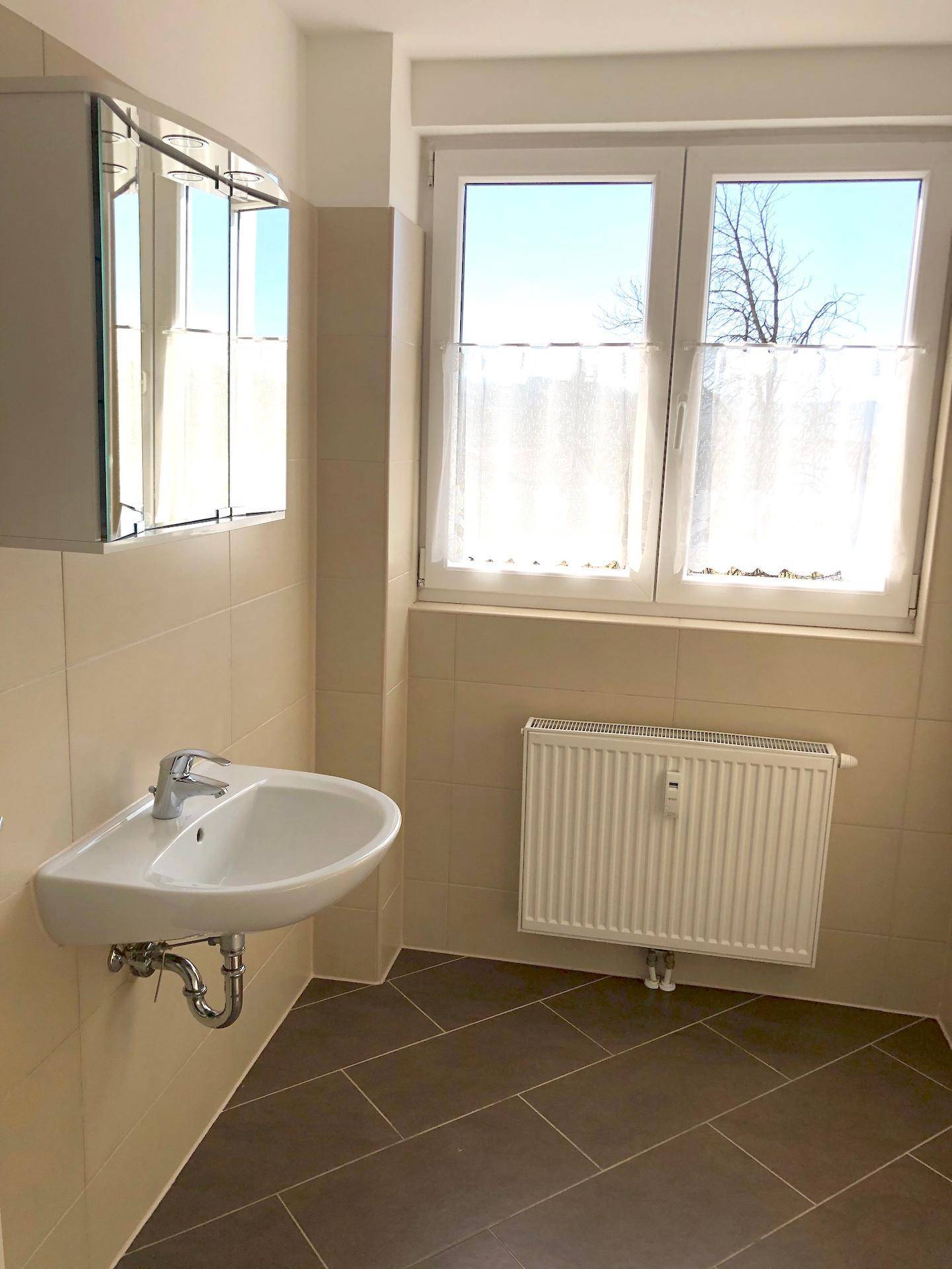 Badezimmer mit Waschbecken, Spiegelschrank und Fenster für gute Belüftung.