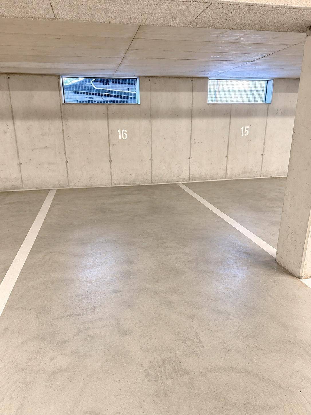 Tiefgarage mit markierten Stellplätzen und Betonwänden, bietet sichere Parkmöglichkeiten.