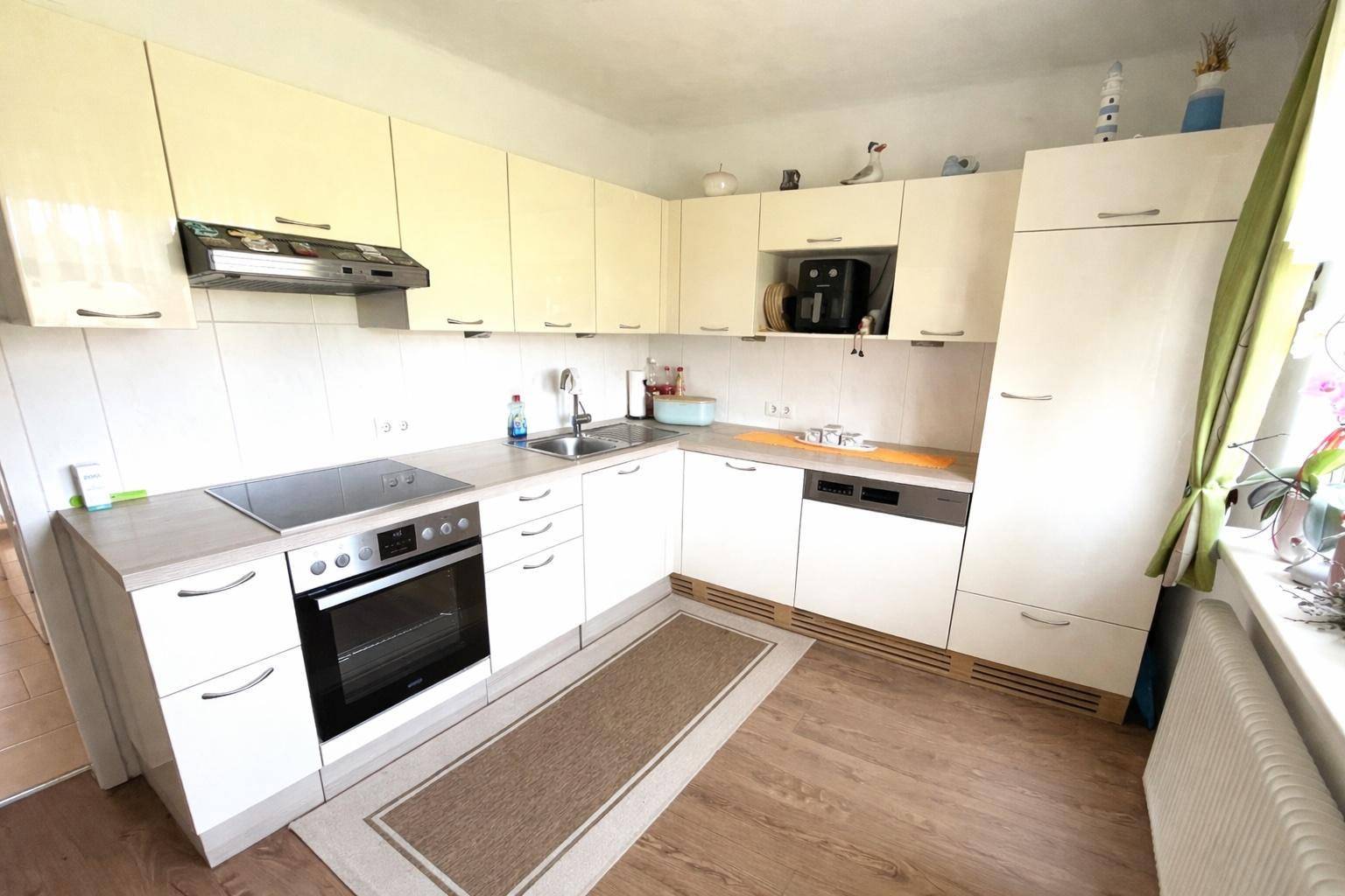 Moderne Küche mit weißen Schränken, Induktionskochfeld und Geschirrspüler.