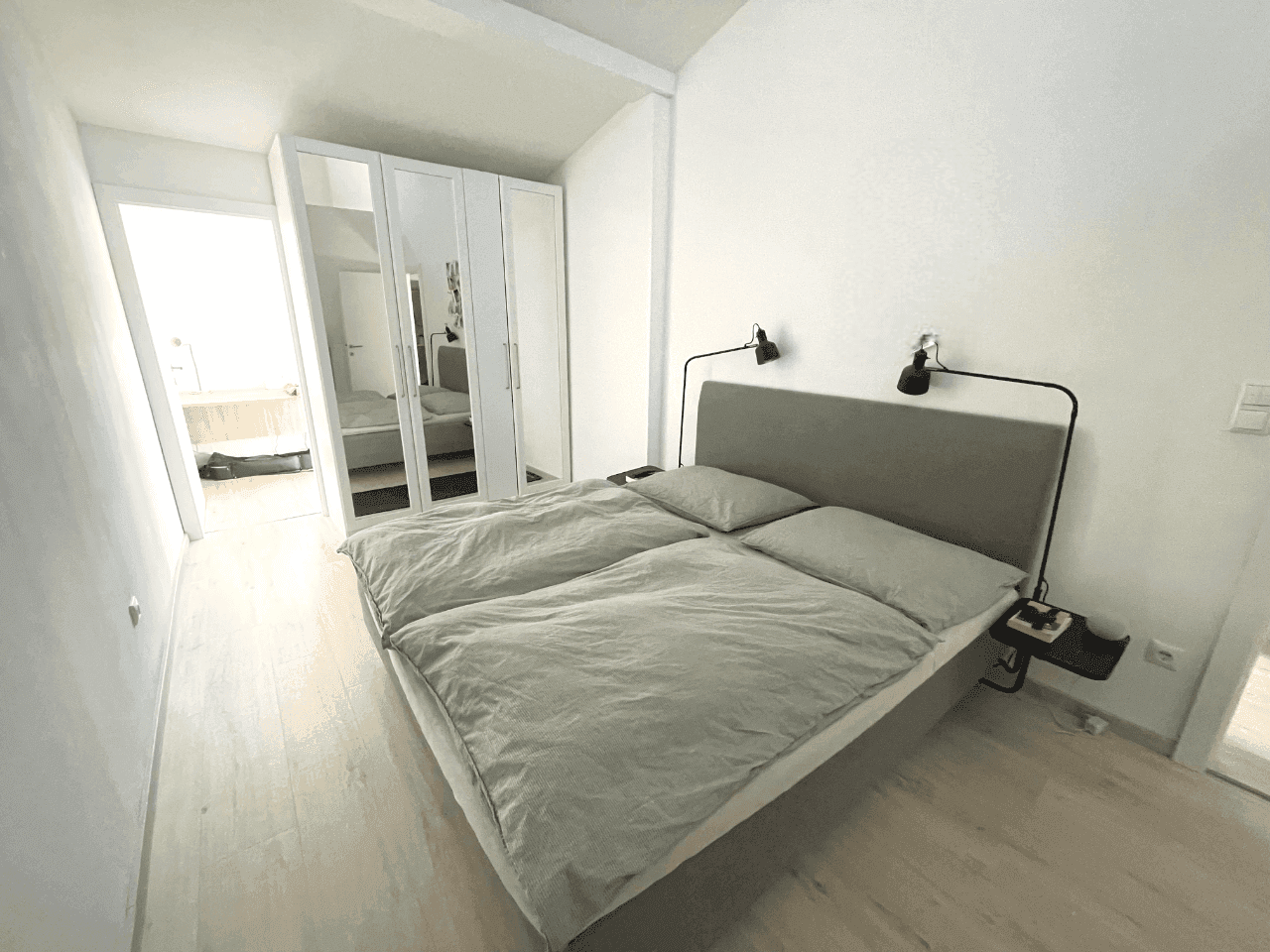 Schlafzimmer mit Doppelbett, Spiegelschrank und Zugang zum Badezimmer.