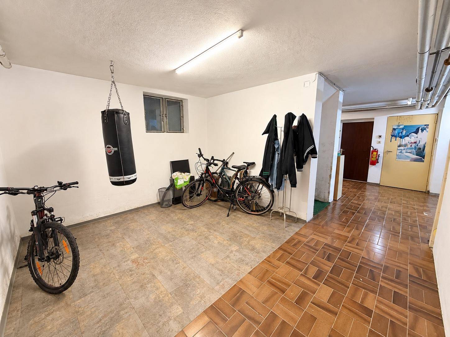Geräumiger Kellerraum mit Fahrrädern und Boxsack, ideal als Hobby- oder Abstellraum.
