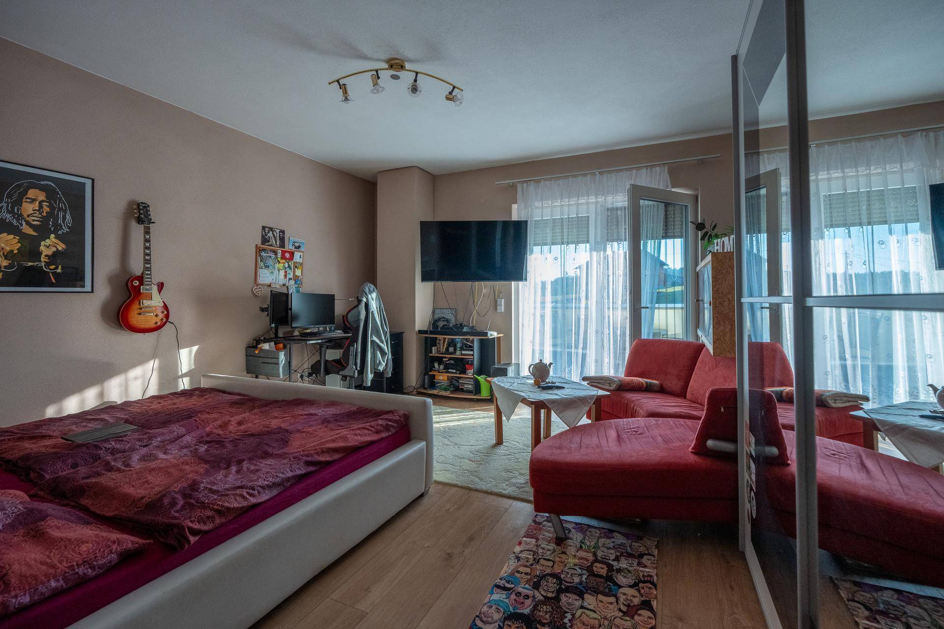 Schlafzimmer mit Doppelbett, Holzfußboden und Zugang zu einem Balkon.