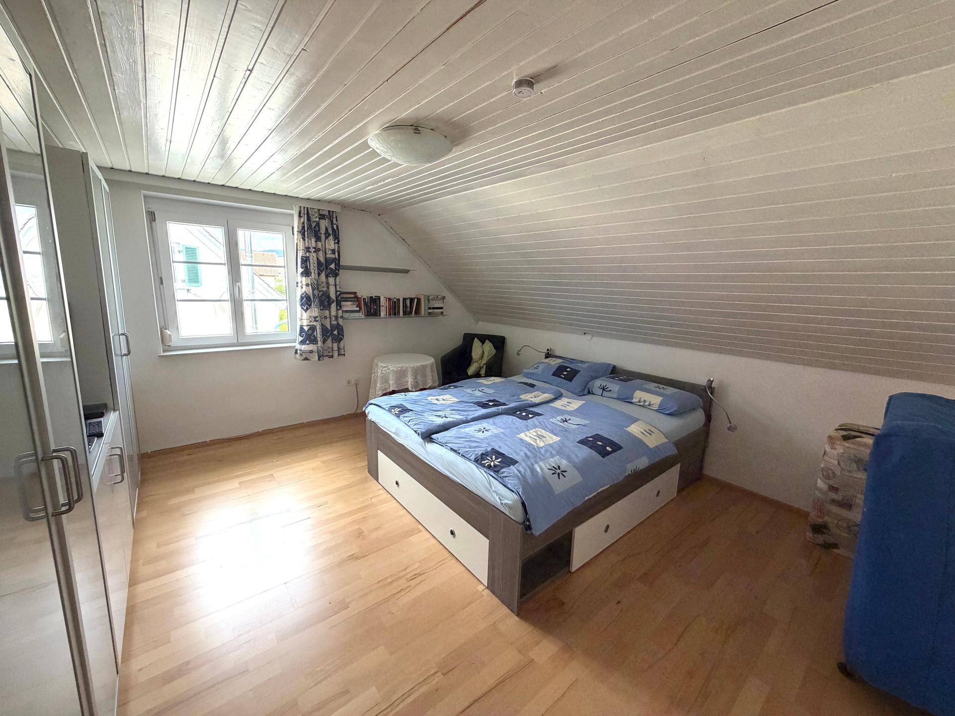 Gemütliches Schlafzimmer mit Doppelbett, Kleiderschrank, Holzboden und Dachschräge.